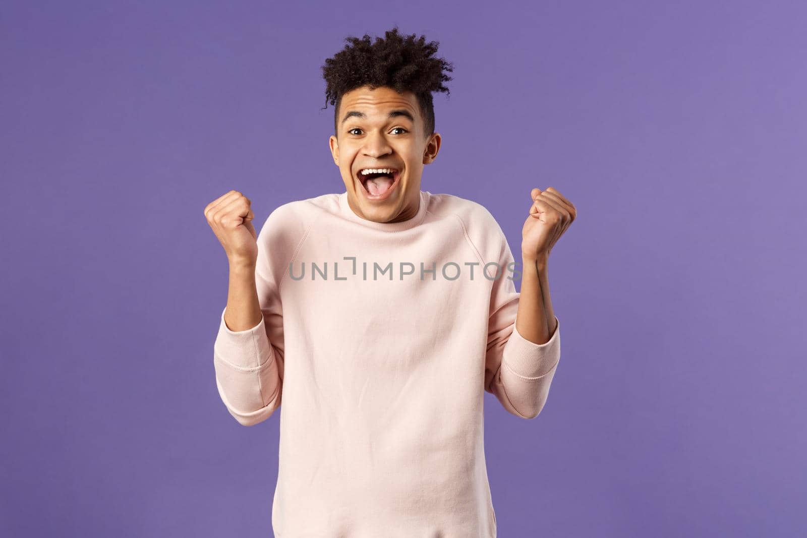 Portrait of happy, cheerful triumphing young hipster guy with dreads, dancing like champion, celebrating success or victory, passed test, fist pump smiling and rejoicing, purple background.