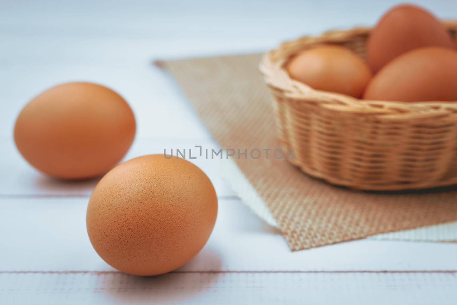 Eggs in the wicker basket on white wooden background for healthy food concept