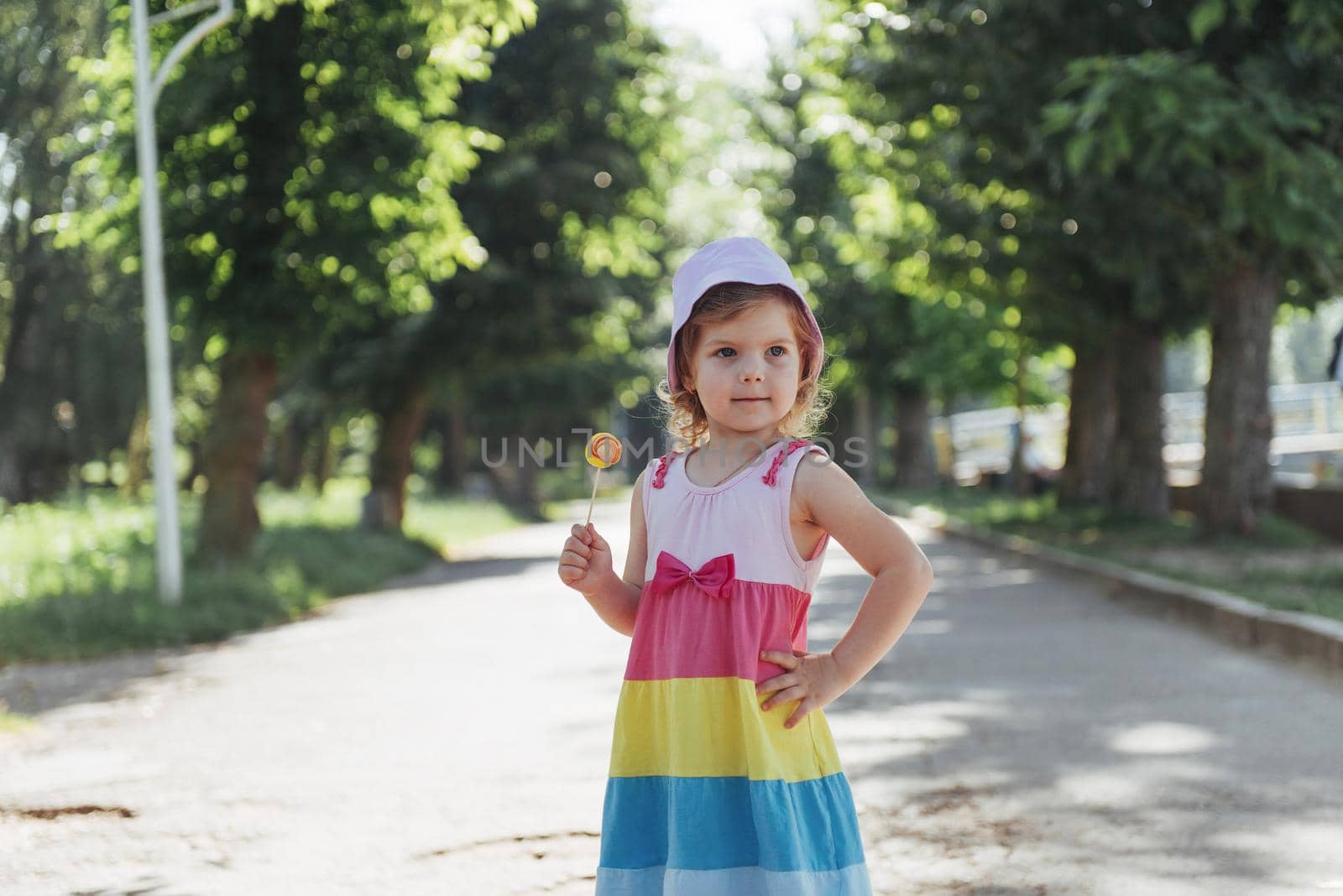 Funny child with candy lollipop, happy little girl eating big sugar lollipop, kid eat sweets.