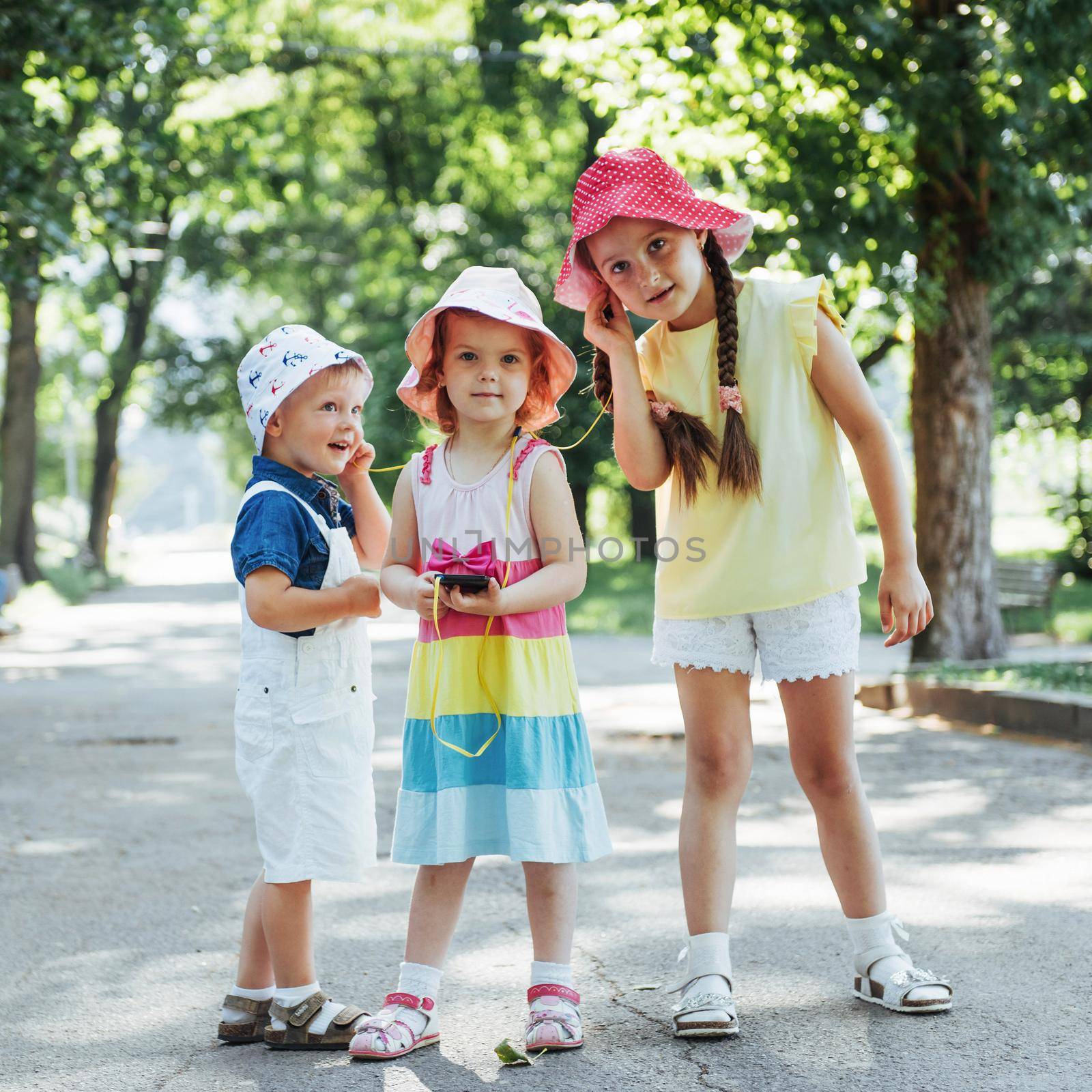 Cute girl and boy listening to music through headphones on the street.