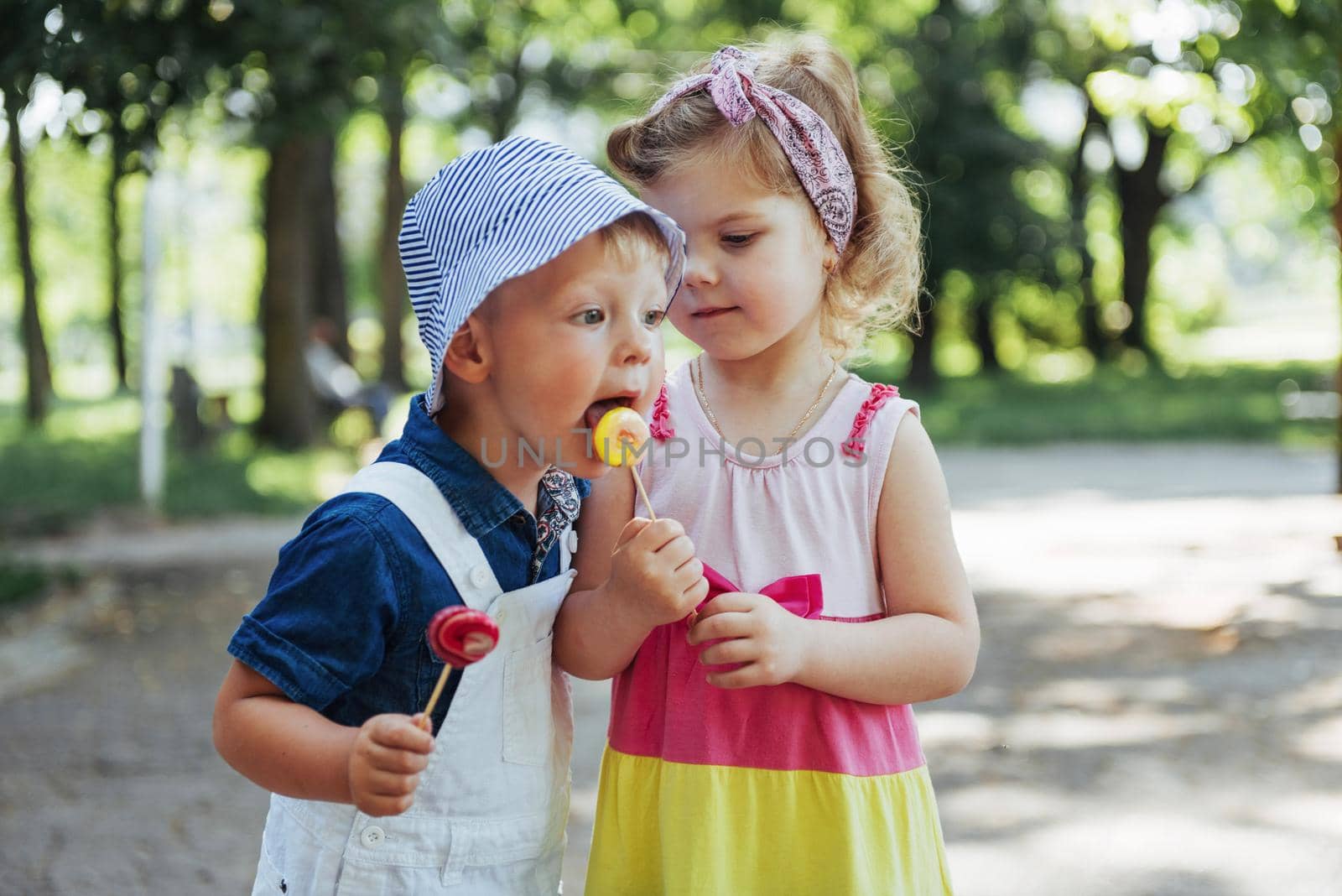 Happy children taste candy on a stick.