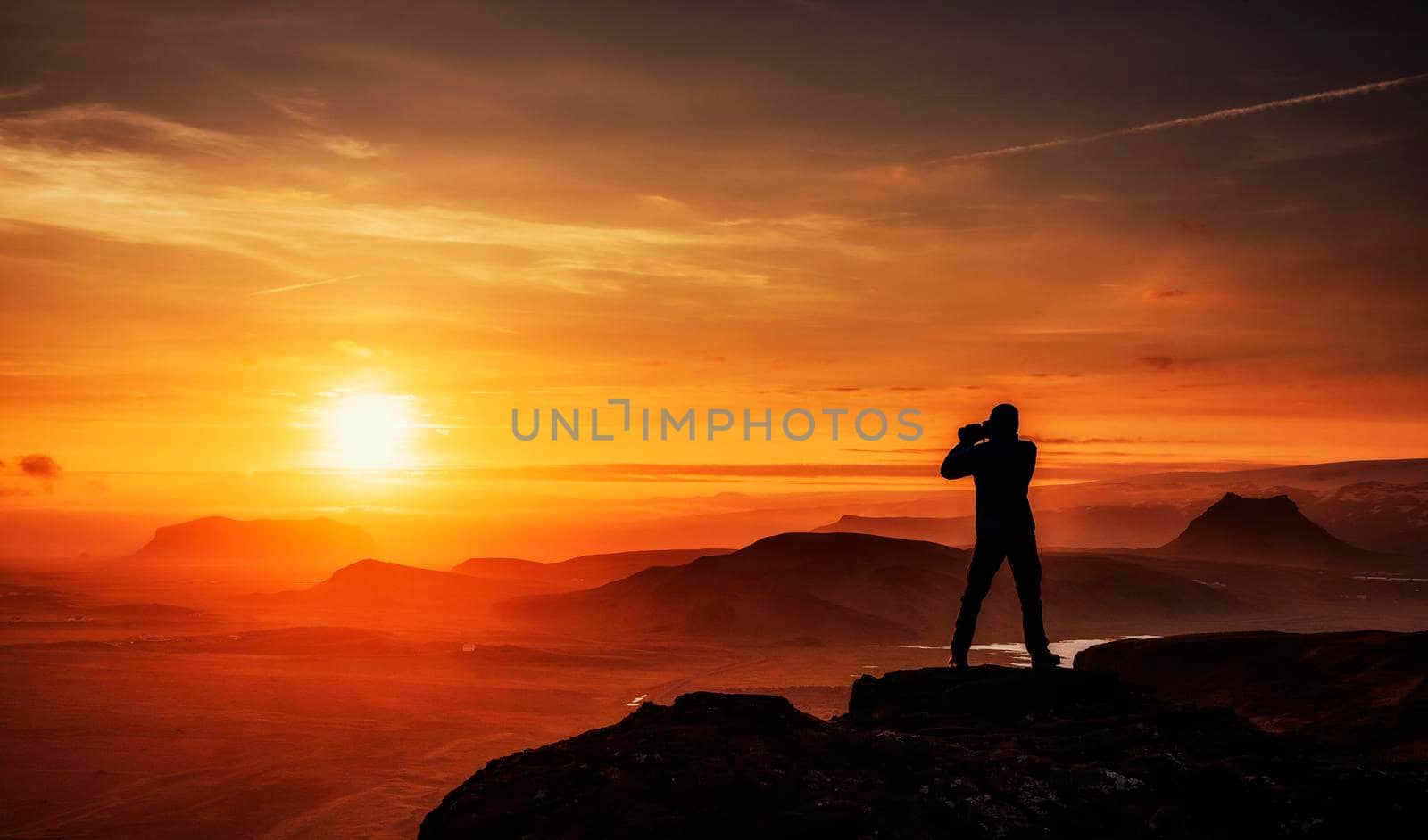 Happy man standing on a cliff at sunset.