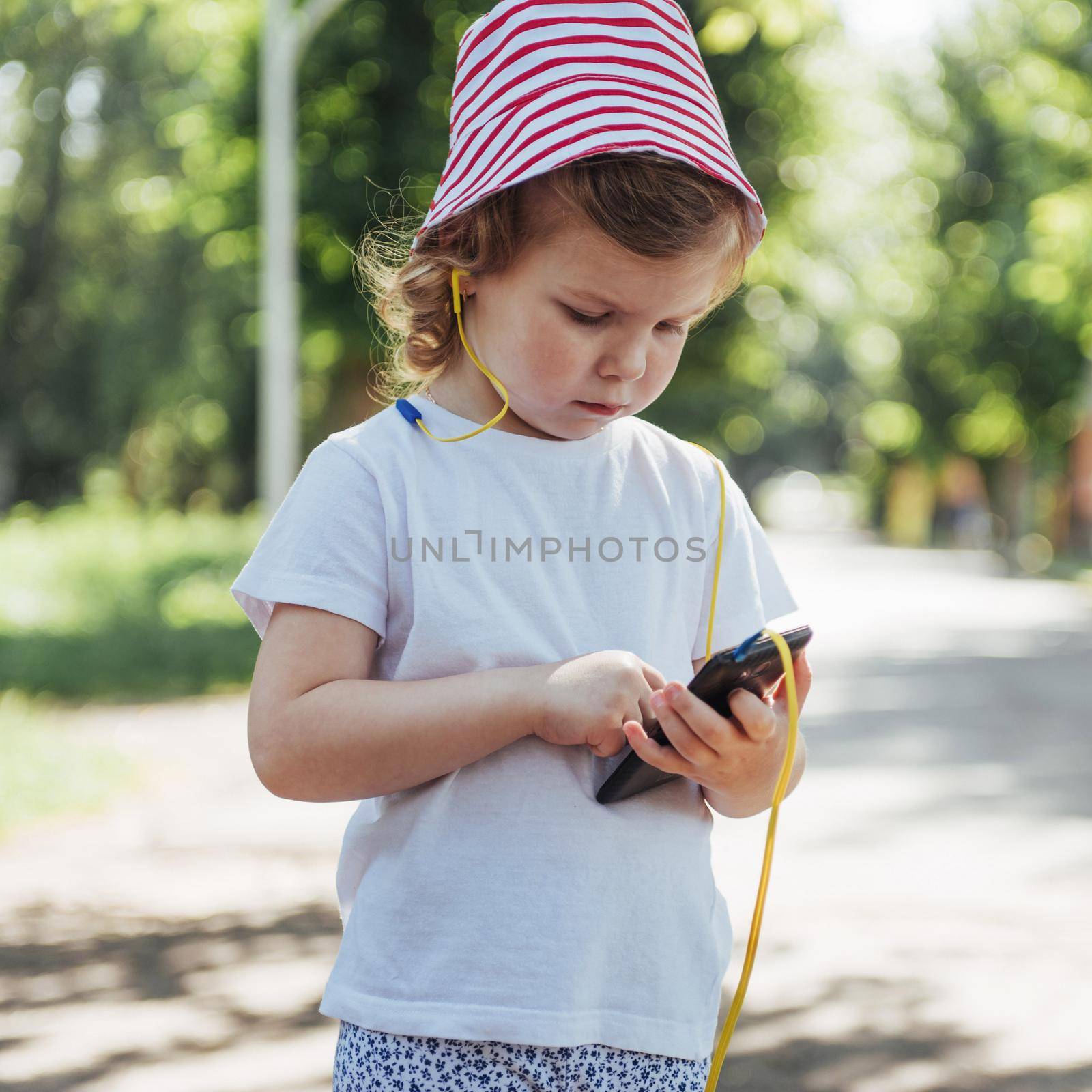 Cute girl listening to music with headphones outdoors.