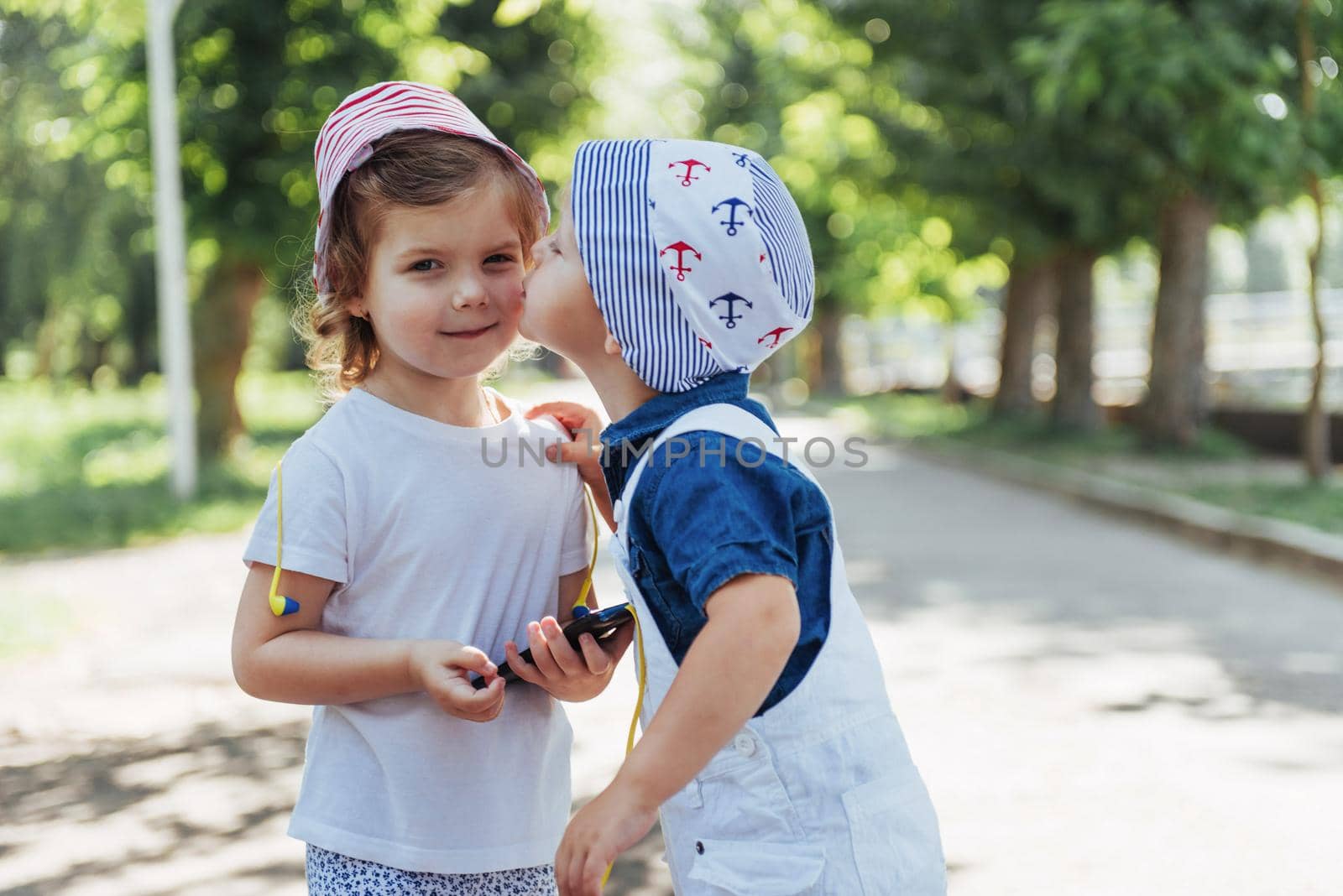 Cute girl and boy listening to music through headphones on the street.