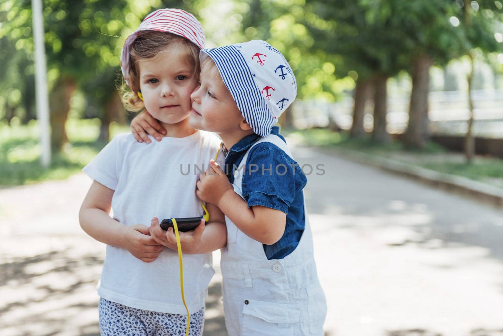 portrait of a little girl and her brother. Children playing outdoors on a sunny summer day. Family holidays.