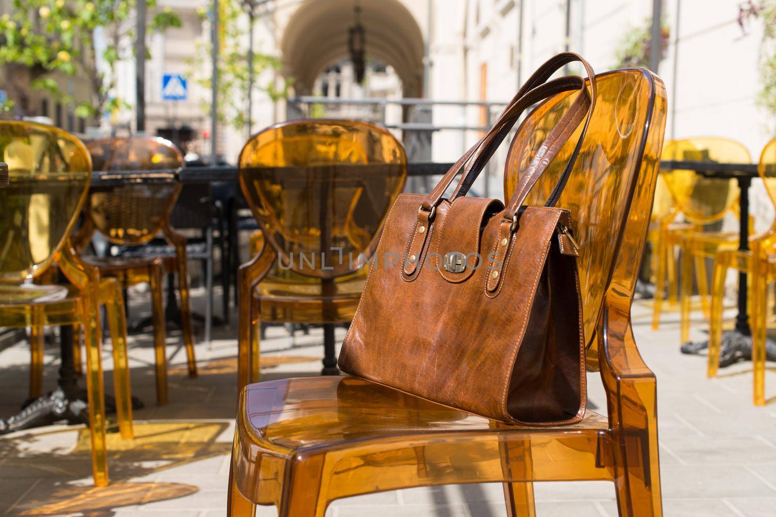 close-up photo of yellow leather bag on a stylish plastic chair. Outdoor photo