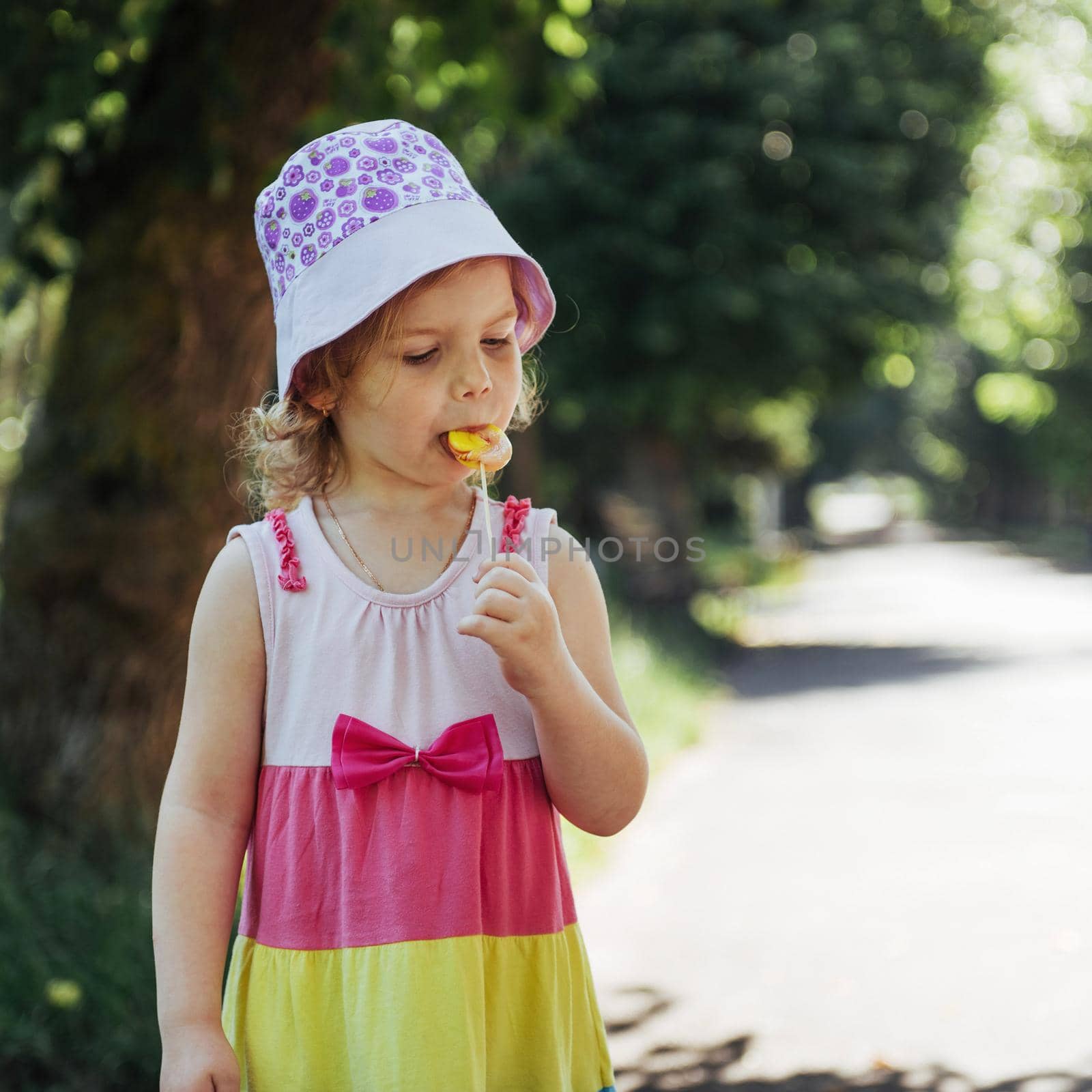 Funny child with candy lollipop, happy little girl eating big sugar lollipop, kid eat sweets.