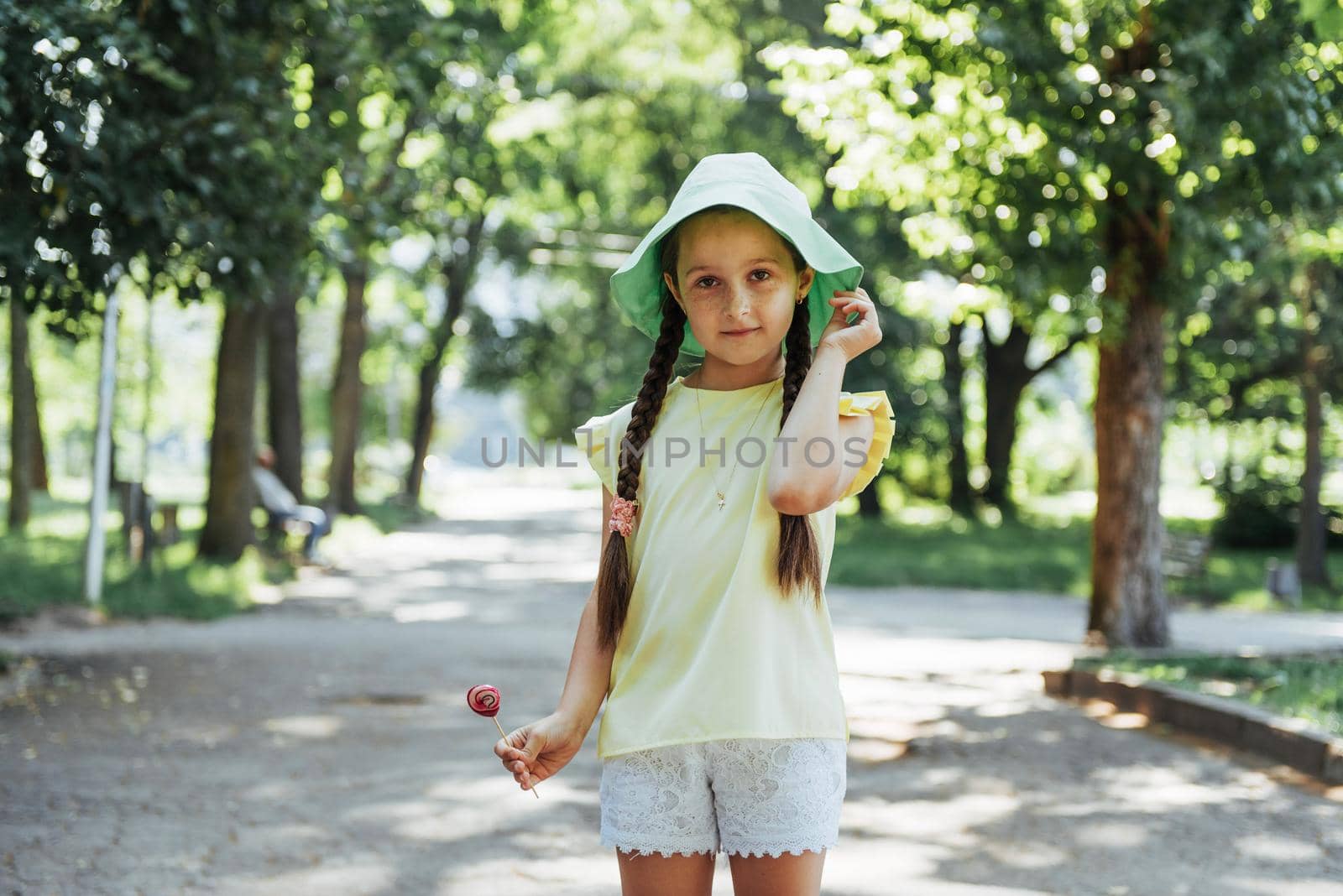 Funny child with candy lollipop, happy little girl eating big sugar lollipop, kid eat sweets.