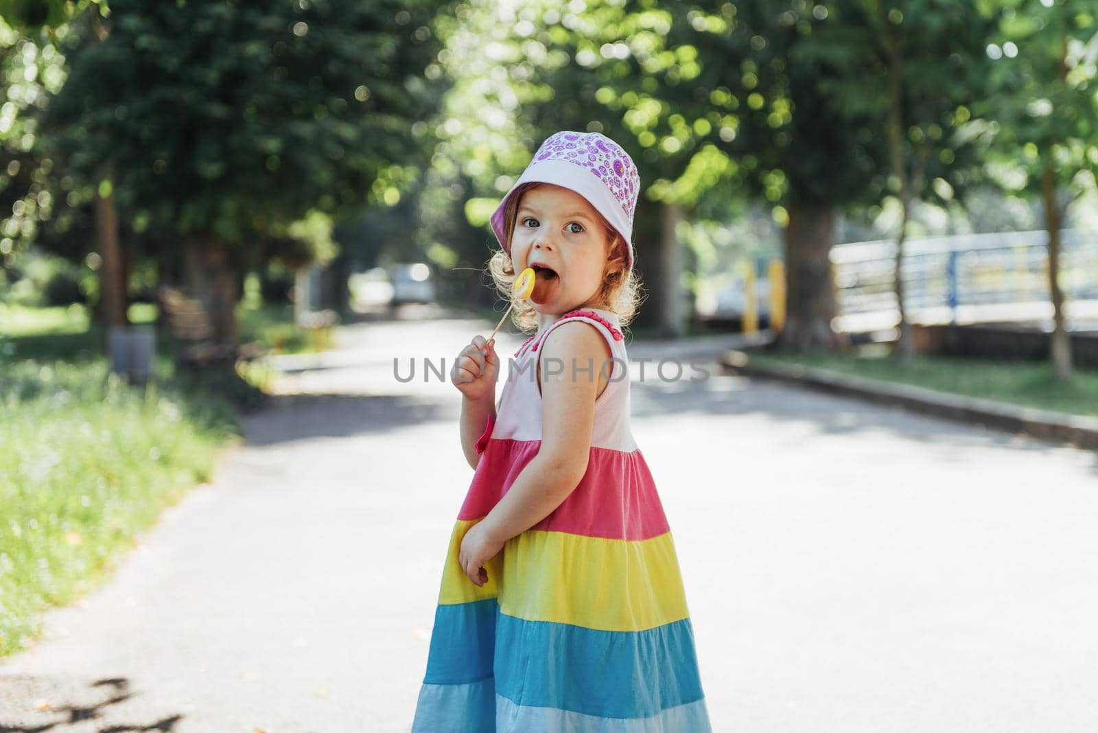 Funny child with candy lollipop, happy little girl eating big sugar lollipop, kid eat sweets.