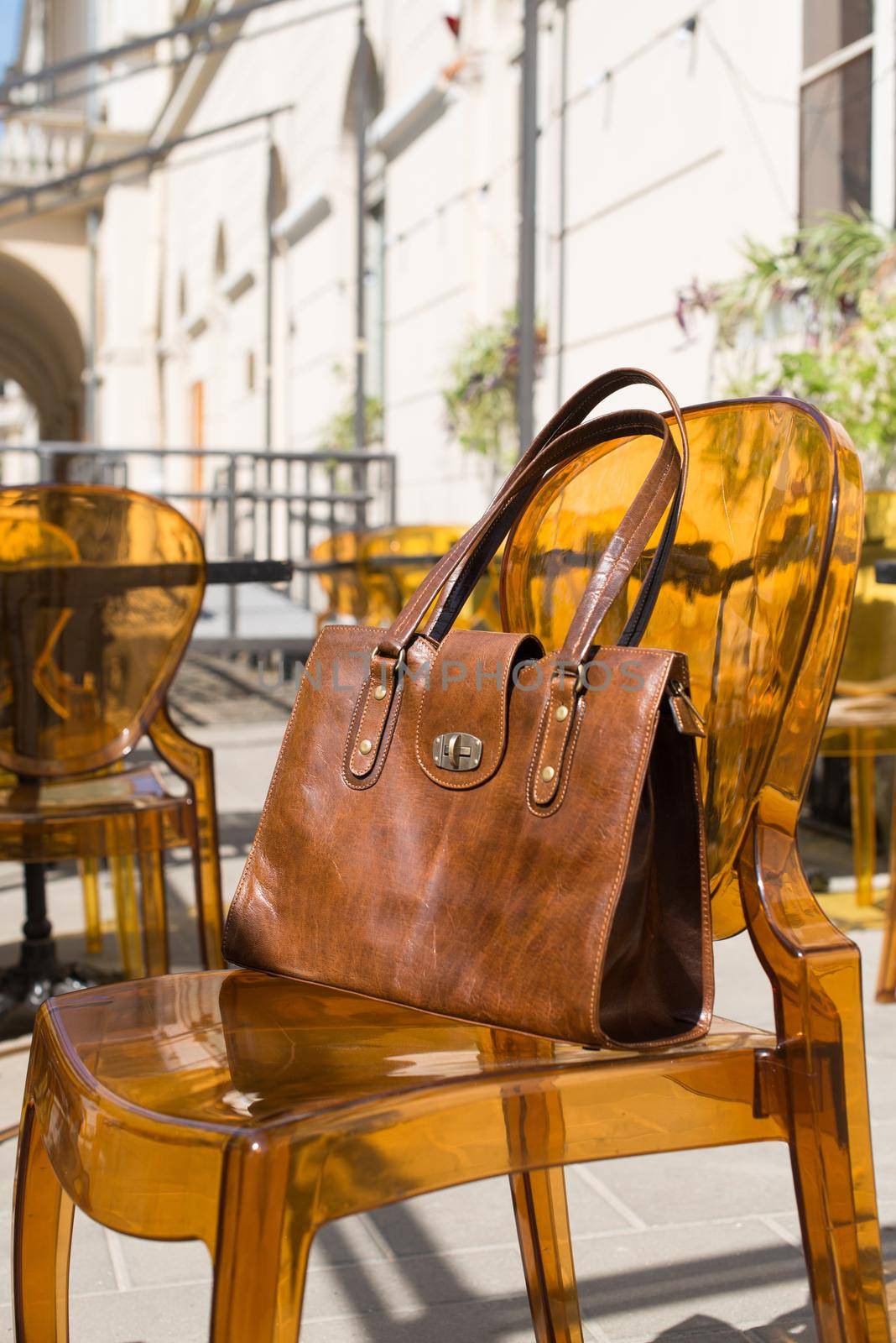 close-up photo of yellow leather bag on a stylish plastic chair. Outdoor photo