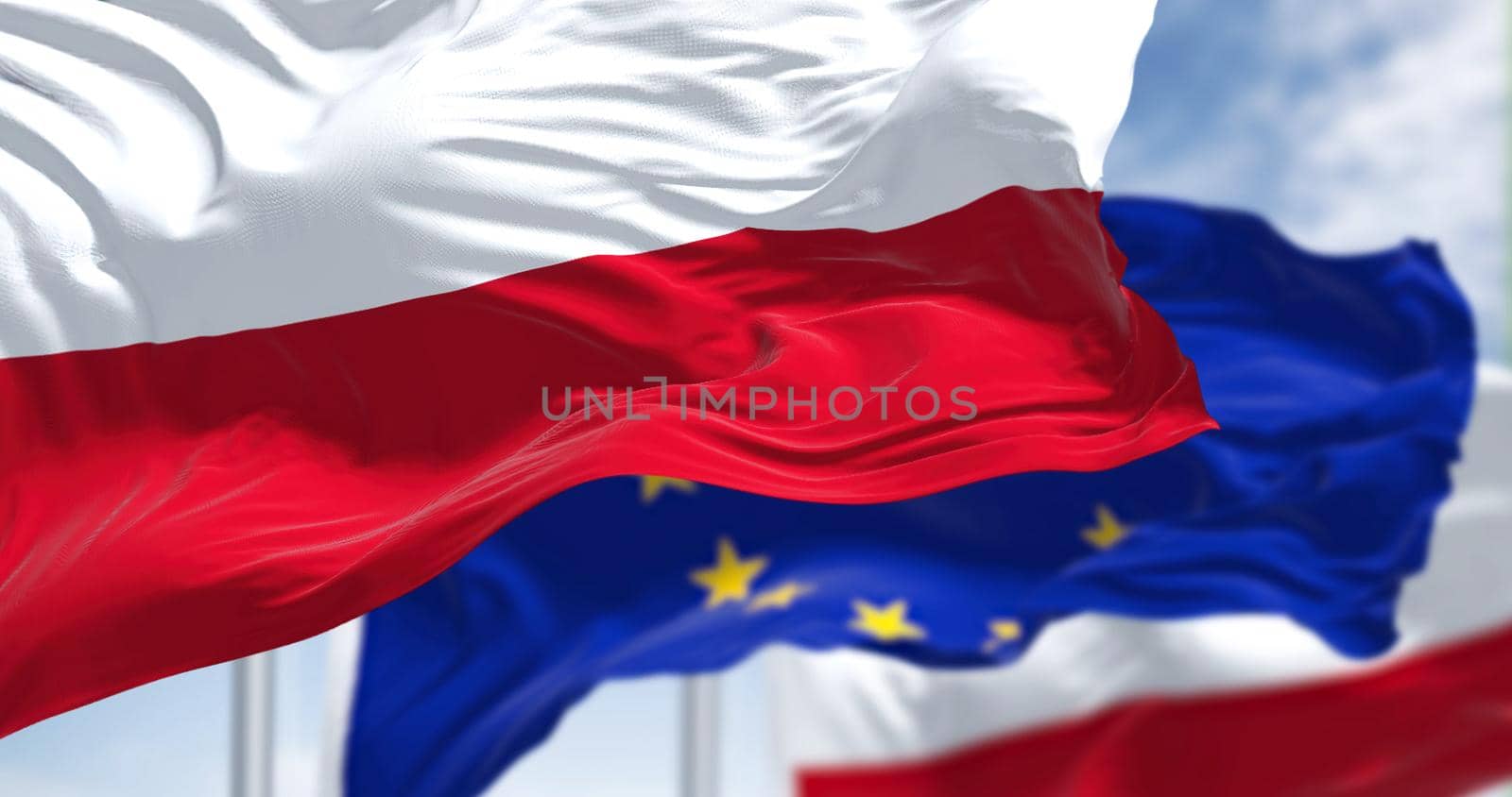 Detail of the national flag of Poland waving in the wind with blurred european union flag in the background by rarrarorro