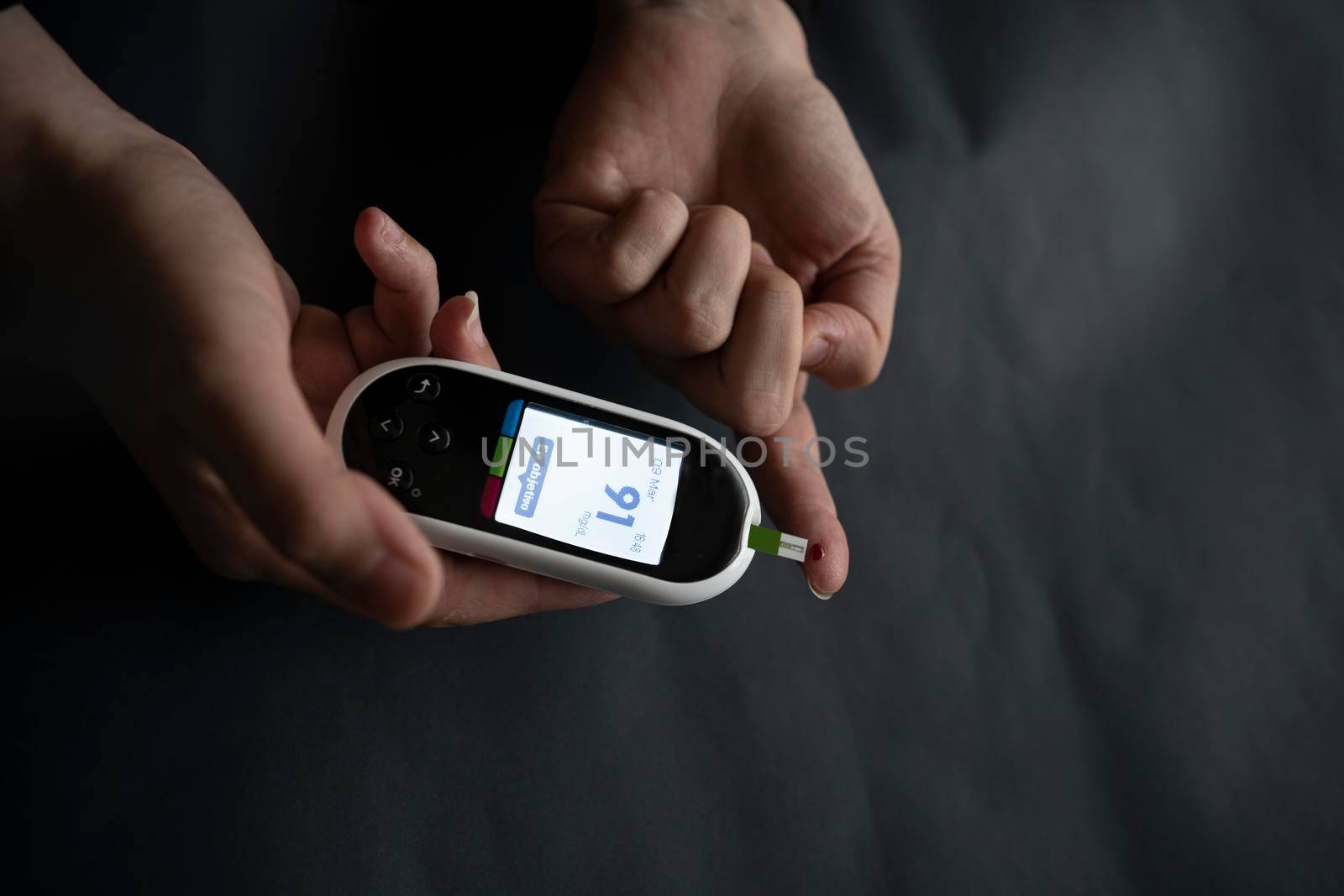 Caucasian young woman using digital glucometer at home. by barcielaphoto