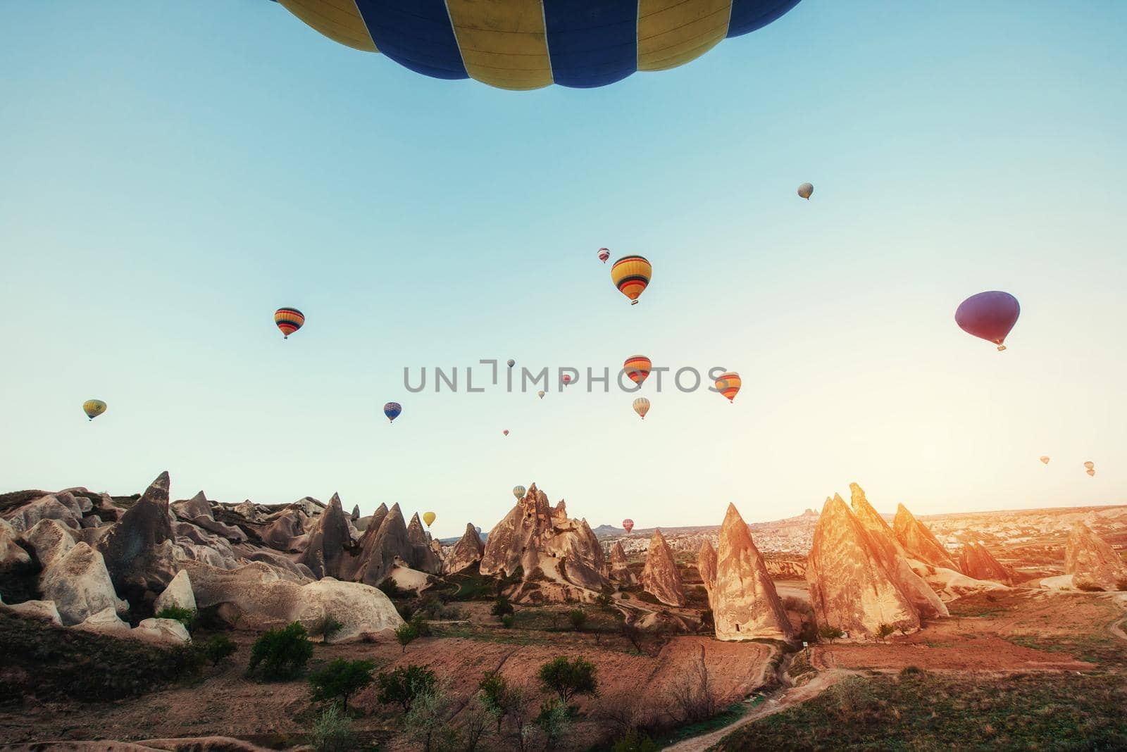 Colorful hot air balloons flying over Red valley at Cappadocia, Anatolia, Turkey. Volcanic mountains in Goreme national park.