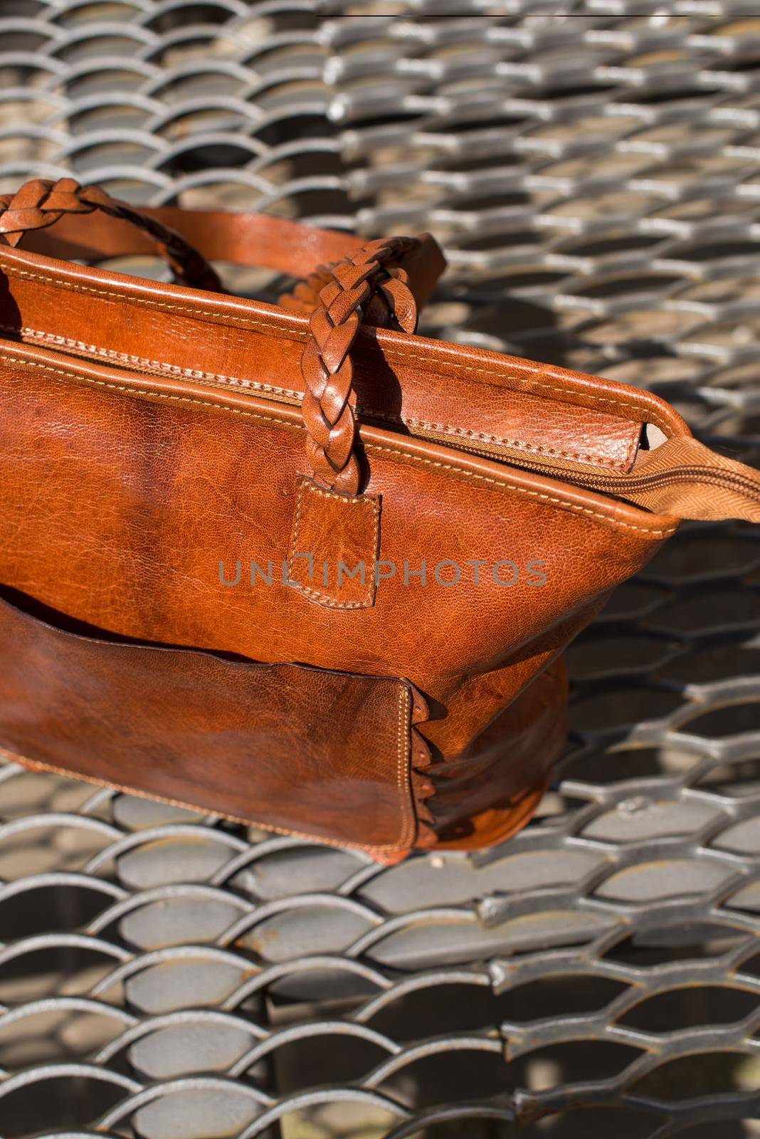 close-up photo of orange leather bag on a metal texture background. outdoor photo