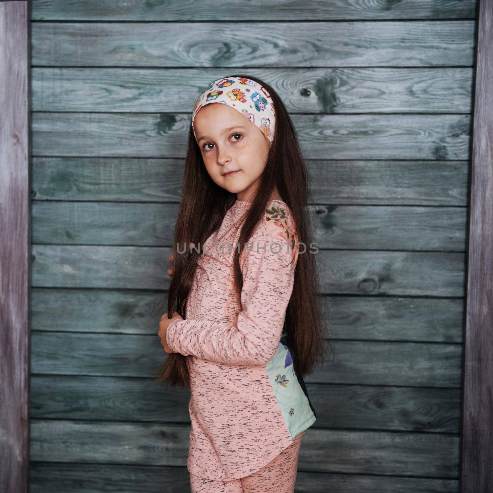 Stylish teenage girl leaning against a wall and looking at the camera