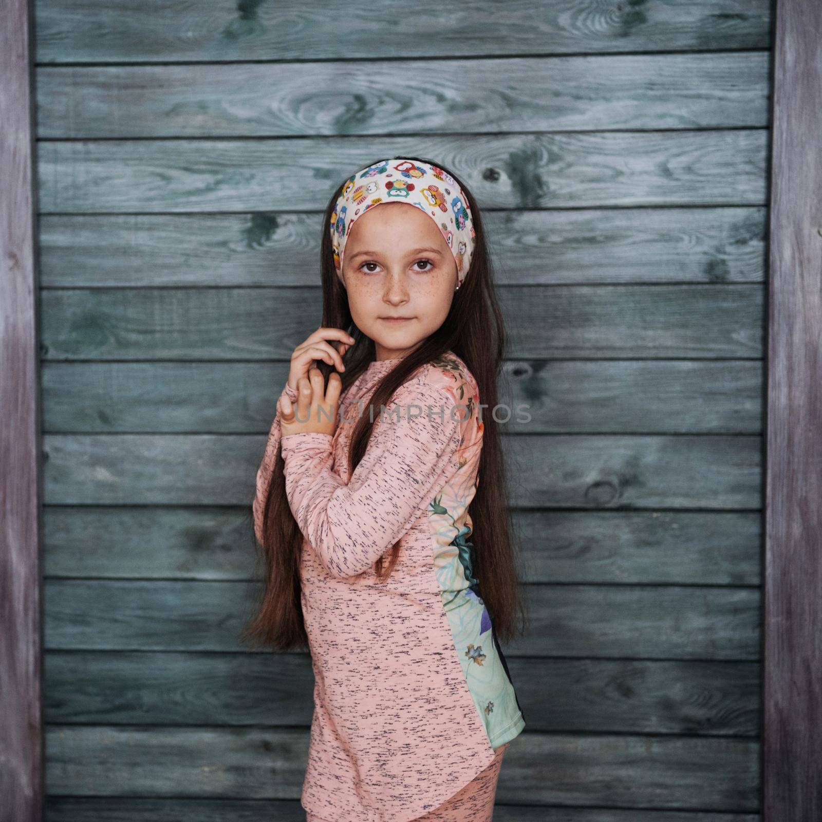 Stylish teenage girl leaning against a wall and looking at the camera
