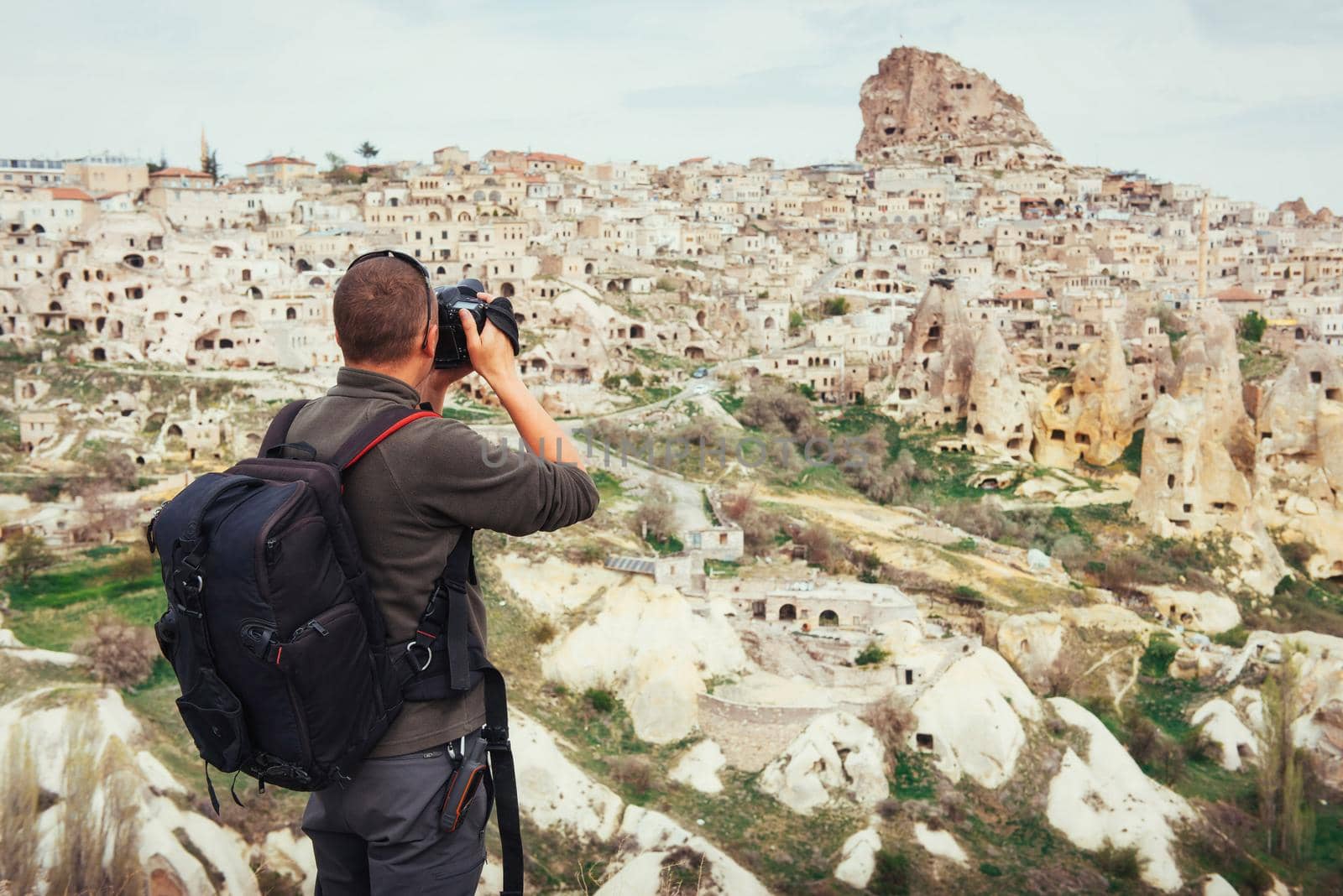 man photographs the ancient city and the castle Uchhysar dug from the mountains. Cappadocia, Turkey