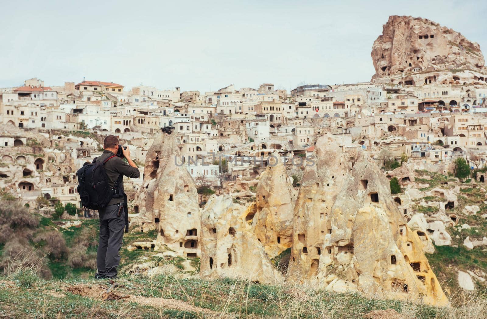 man photographs the ancient city and the castle Uchhysar dug from the mountains. Cappadocia, Turkey