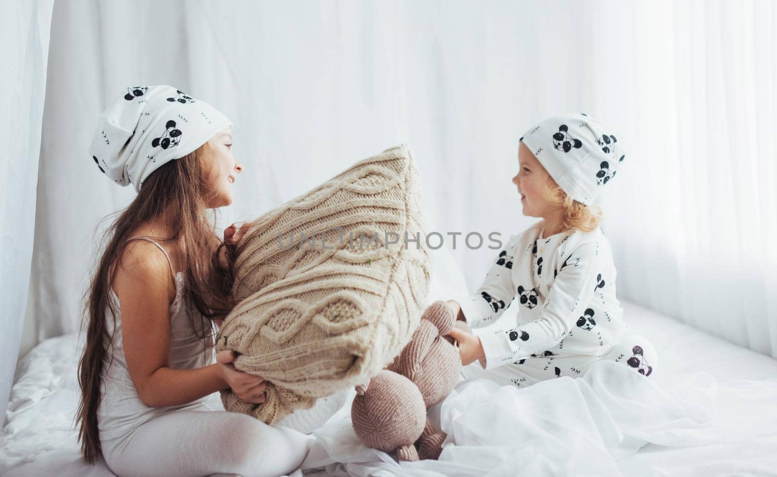 Children in soft warm pajamas playing in bed