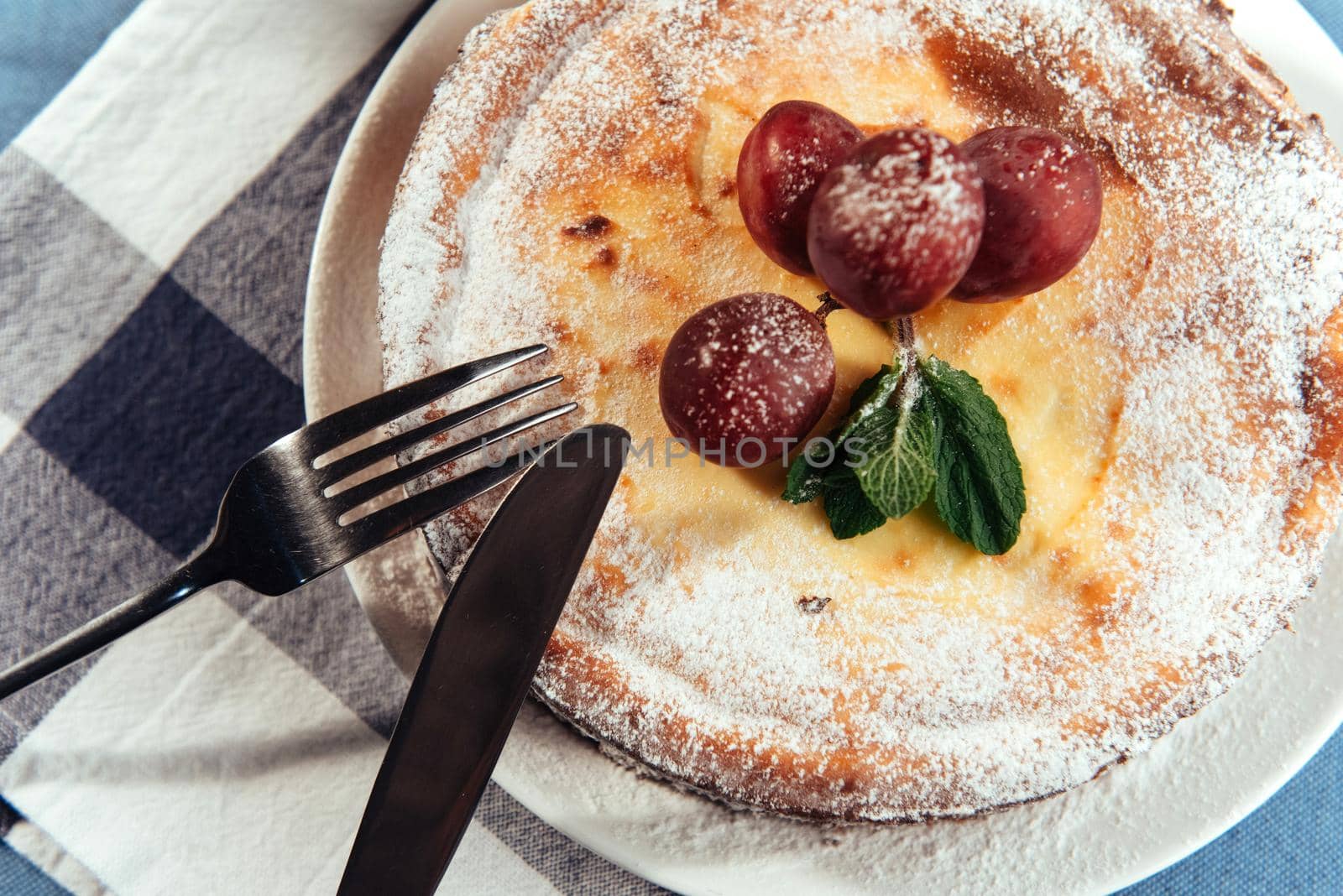 Fresh Creamy traditional cheesecake with grapes and sprinkled with powdered sugar.