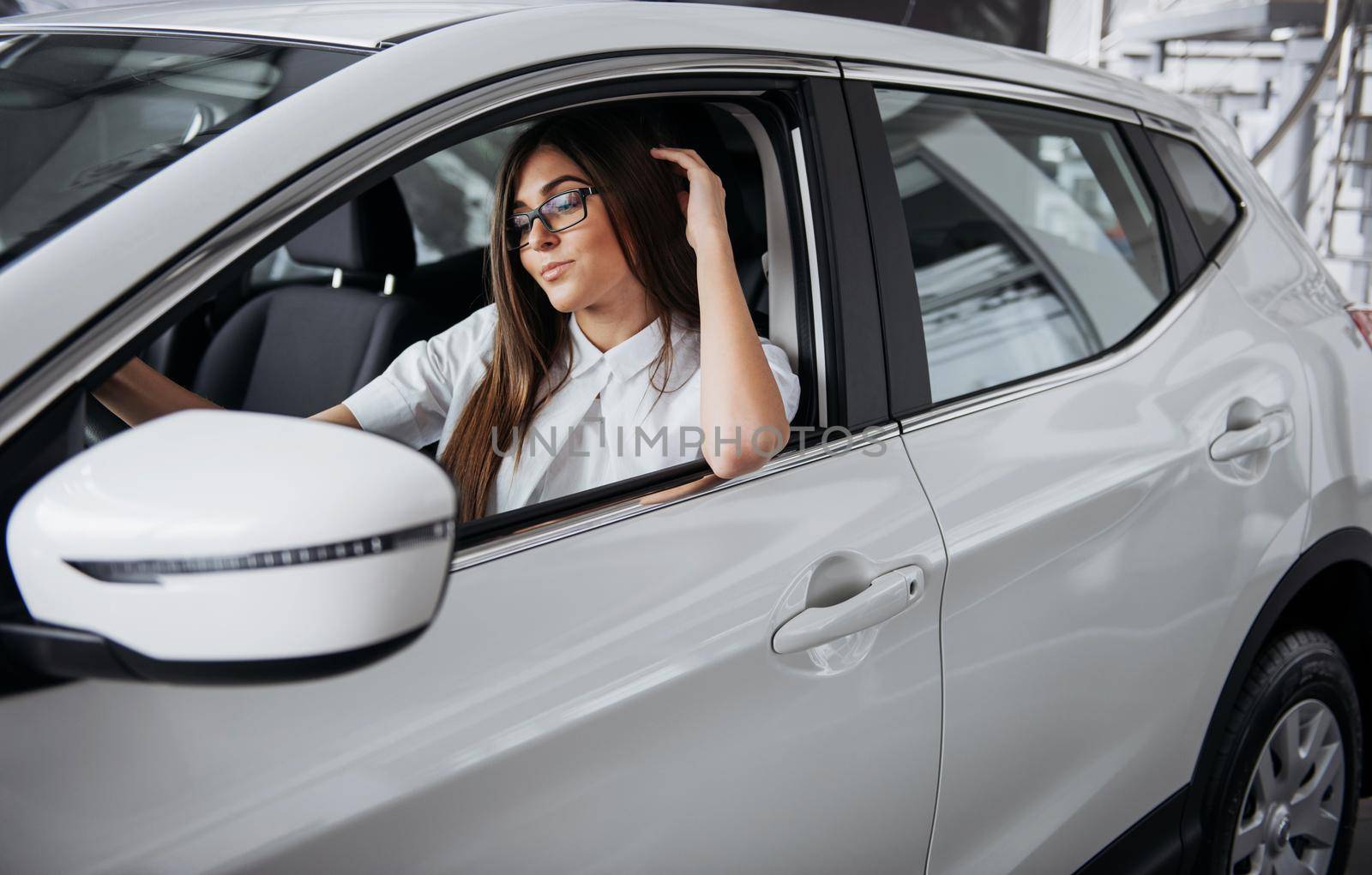 attractive young Caucasian woman looking at the camera from the front seat of the car