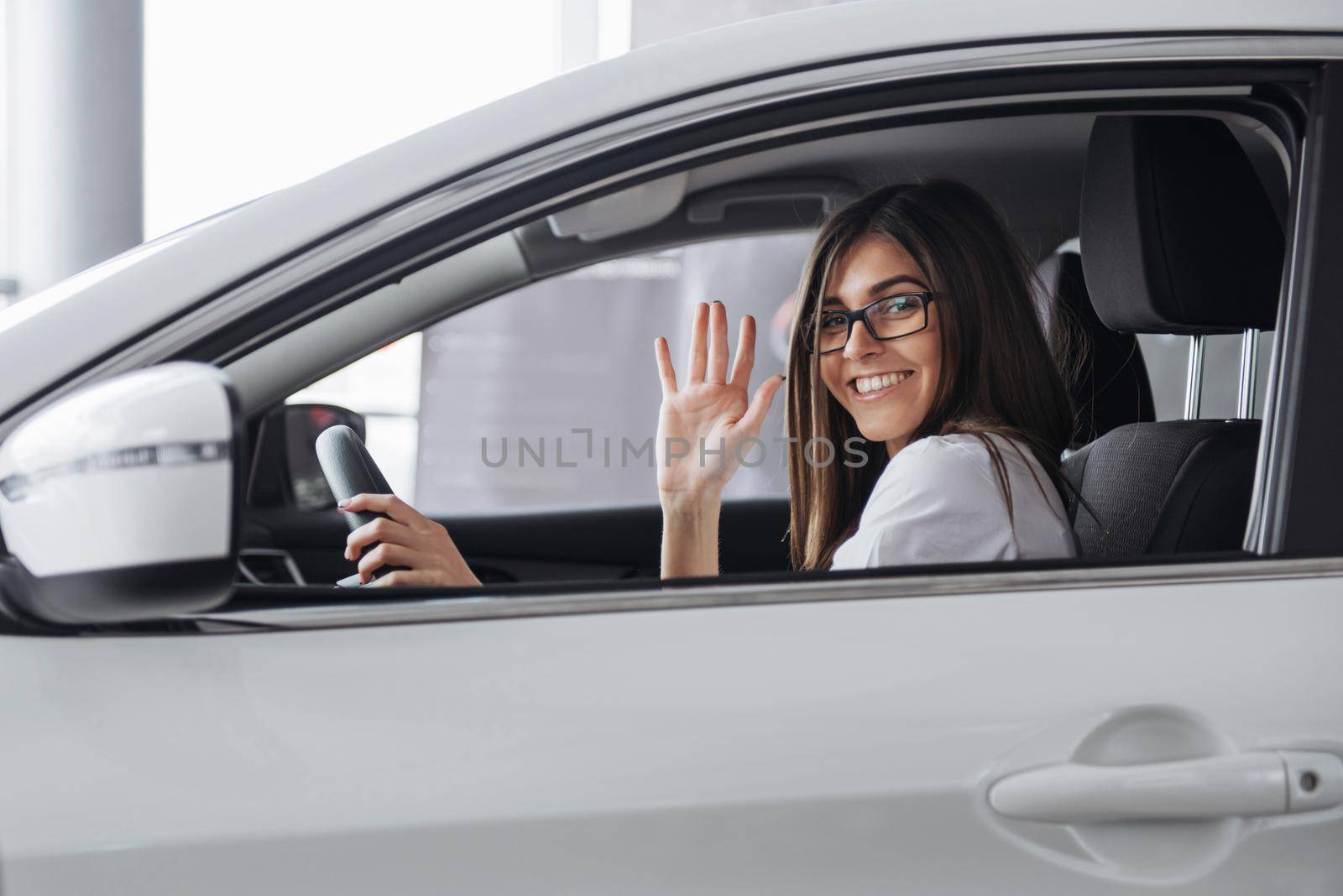 Pretty young woman driving her new car