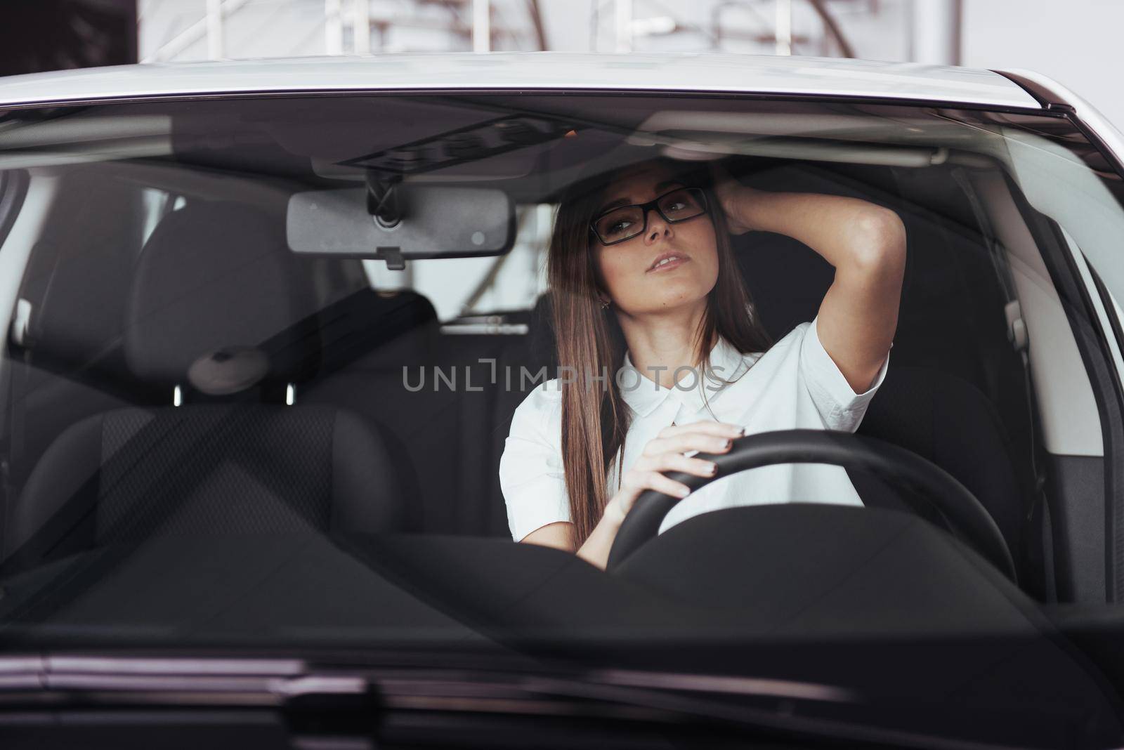 attractive young Caucasian woman looking at the camera from the front seat of the car