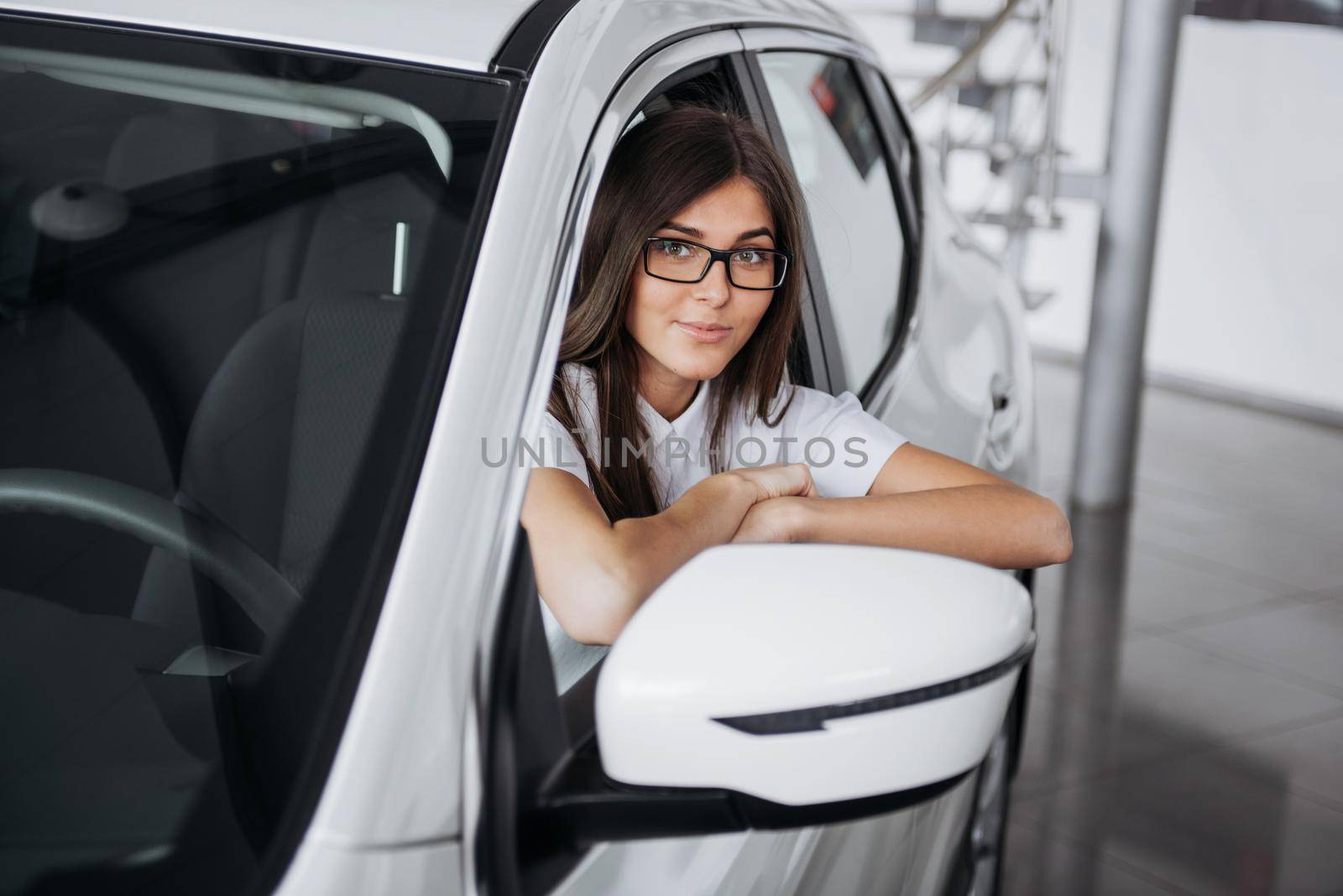 attractive young Caucasian woman looking at the camera from the front seat of the car