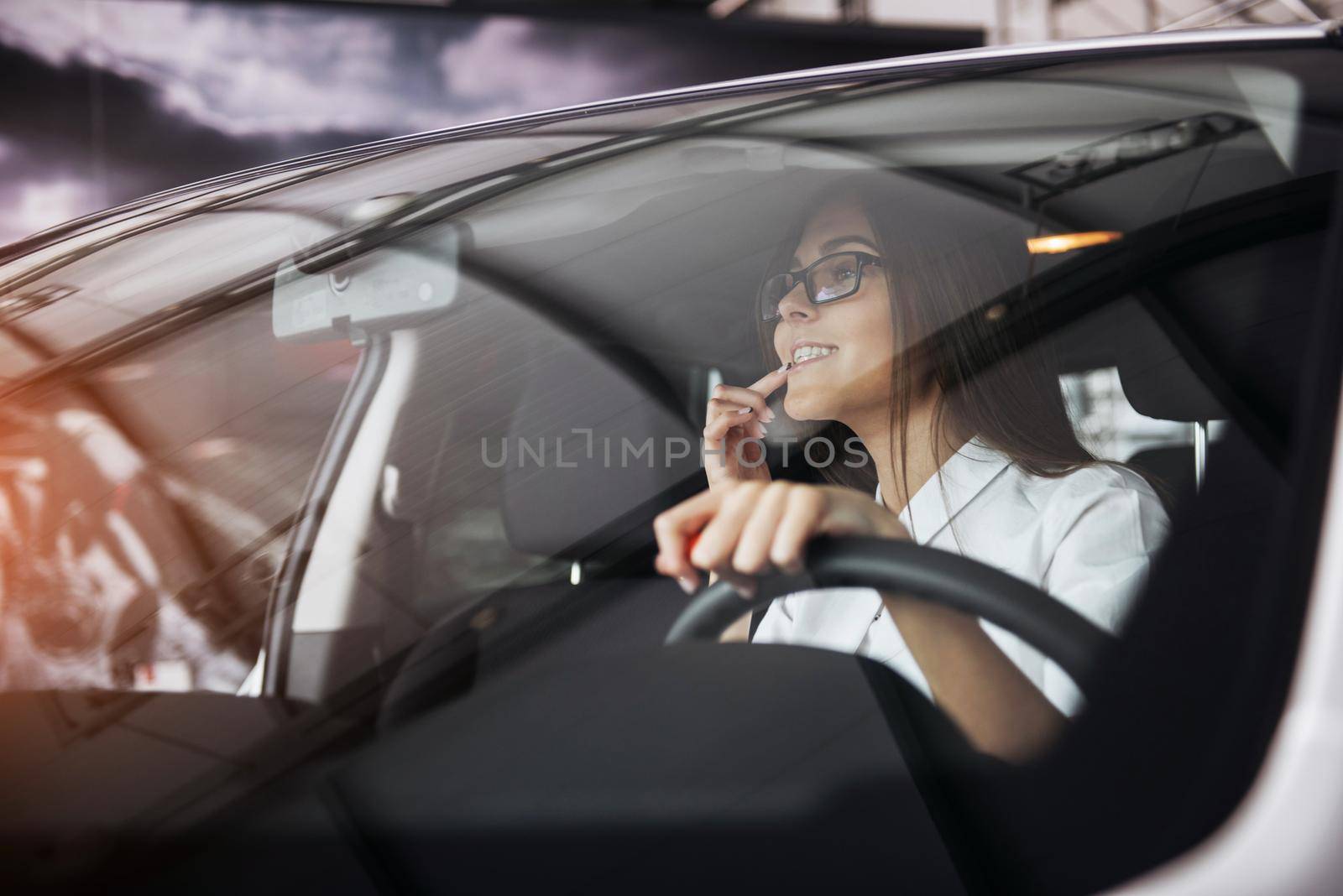 Pretty young woman driving her new car