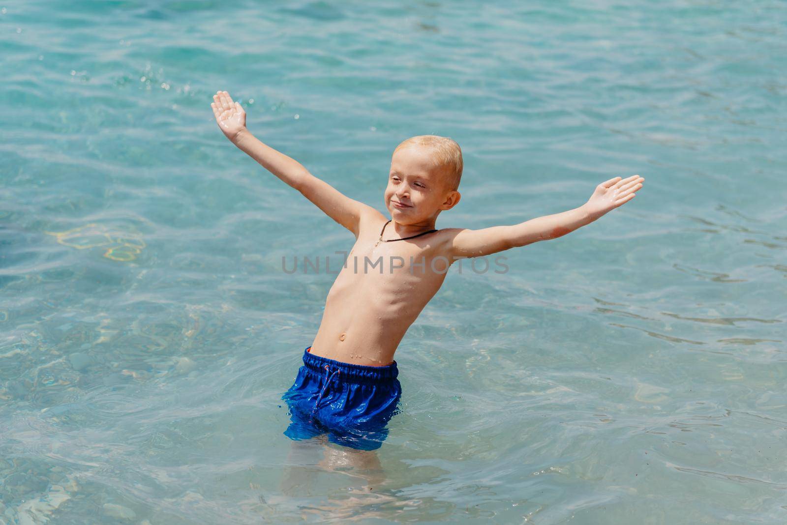 Child learning to swim in the open sea of tropical resort. Kids learn swimming. Exercise and training for young children. Little boy with colorful float board in sport club. Swimming baby or toddler. Happy child boy swims in sea in swimming circle with splash. Blue sky and water. Swimming training. Fun joy activities on vacation in the beach. Childhood moments lifestyle. Freedom careless. boy swim in the sea by Andrii_Ko