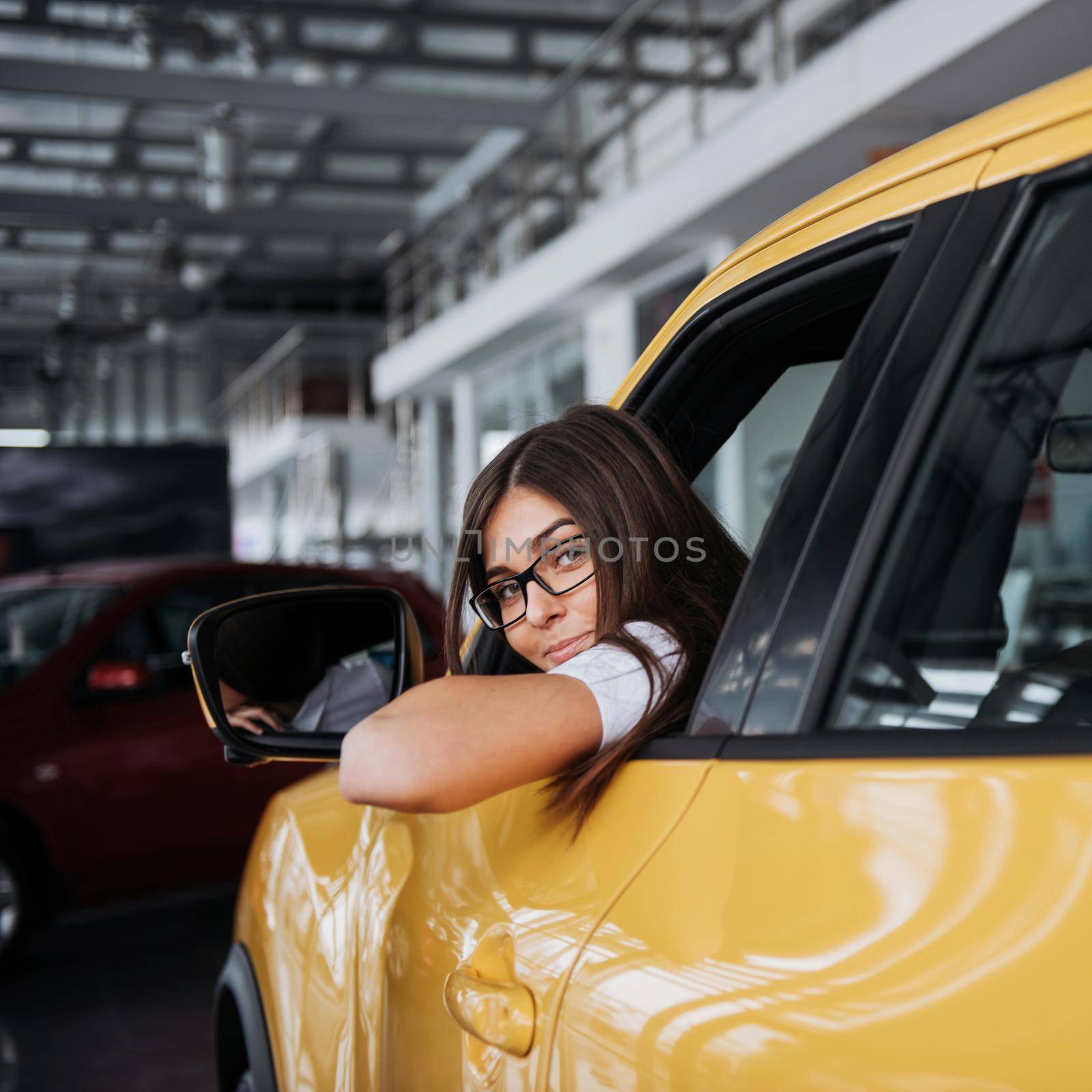 Young woman in her new car smiling by Standret