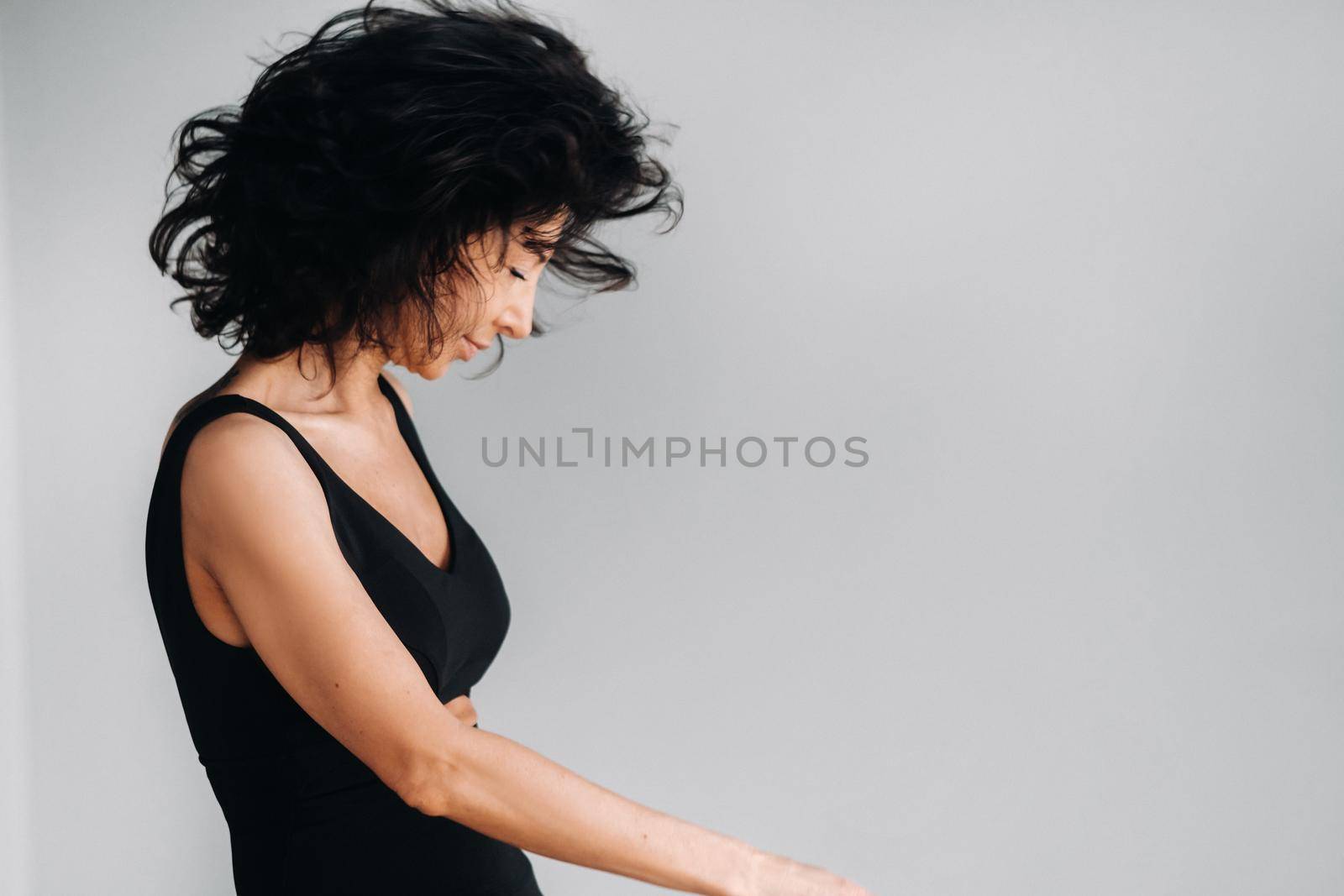 A woman in black sportswear is engaged in dynamic kali meditation in the Yoga hall.