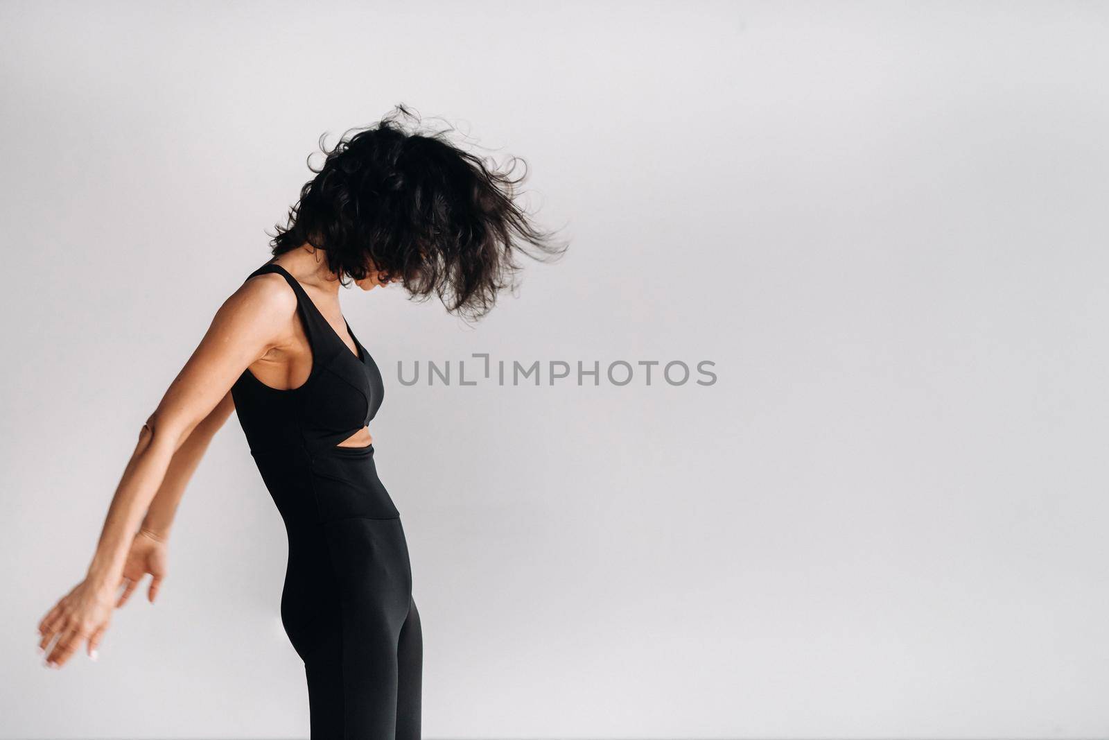 A woman in black sportswear is engaged in dynamic kali meditation in the Yoga hall.