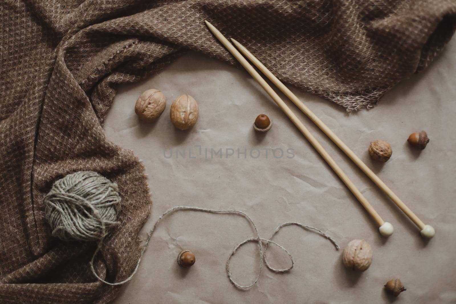 hobby, leisure theme. Yarn and wooden needles on a brown paper texture background with cozy warm plaid, top view, copyspace.