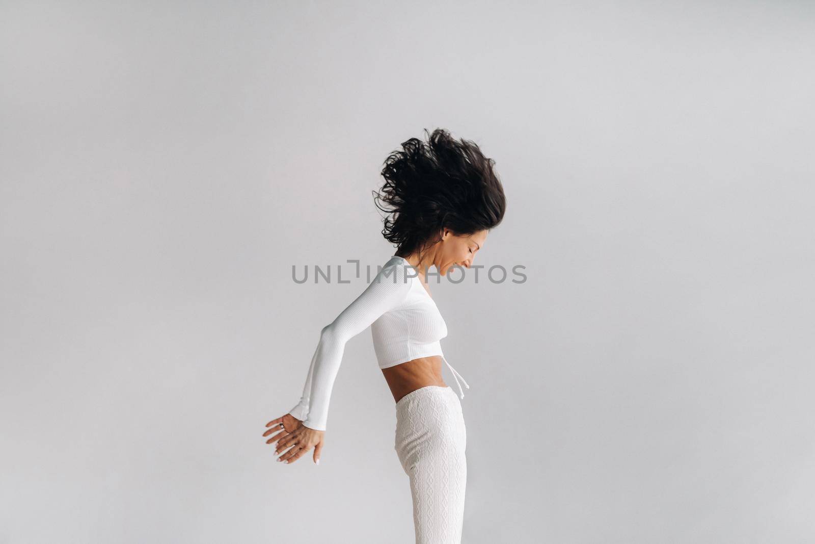 A woman in white sportswear is engaged in dynamic kali meditation in the yoga hall.