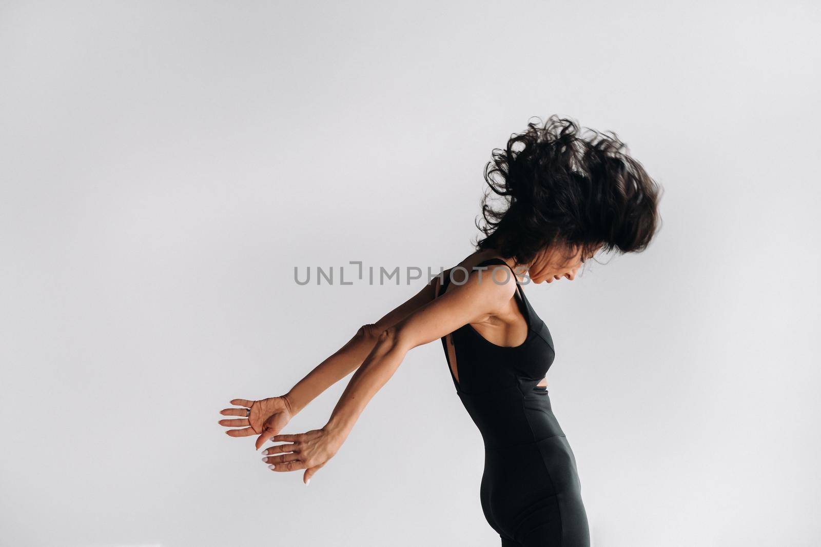 A woman in black sportswear is engaged in dynamic kali meditation in the Yoga hall.