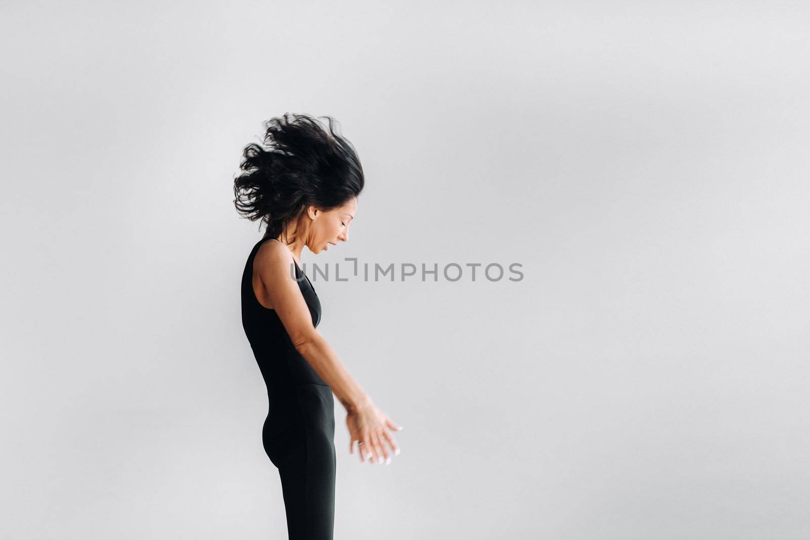 A woman in black sportswear is engaged in dynamic kali meditation in the Yoga hall.