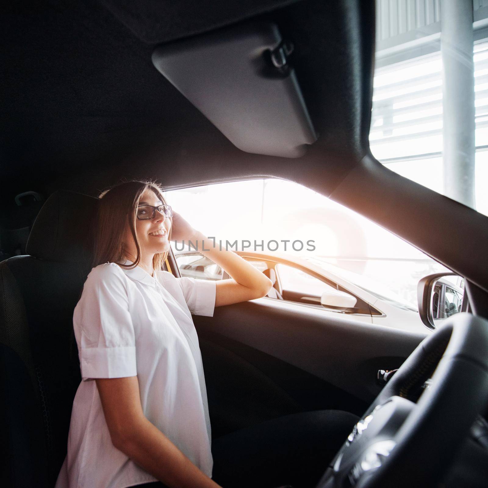 attractive young Caucasian woman looking at the camera from the front seat of the car