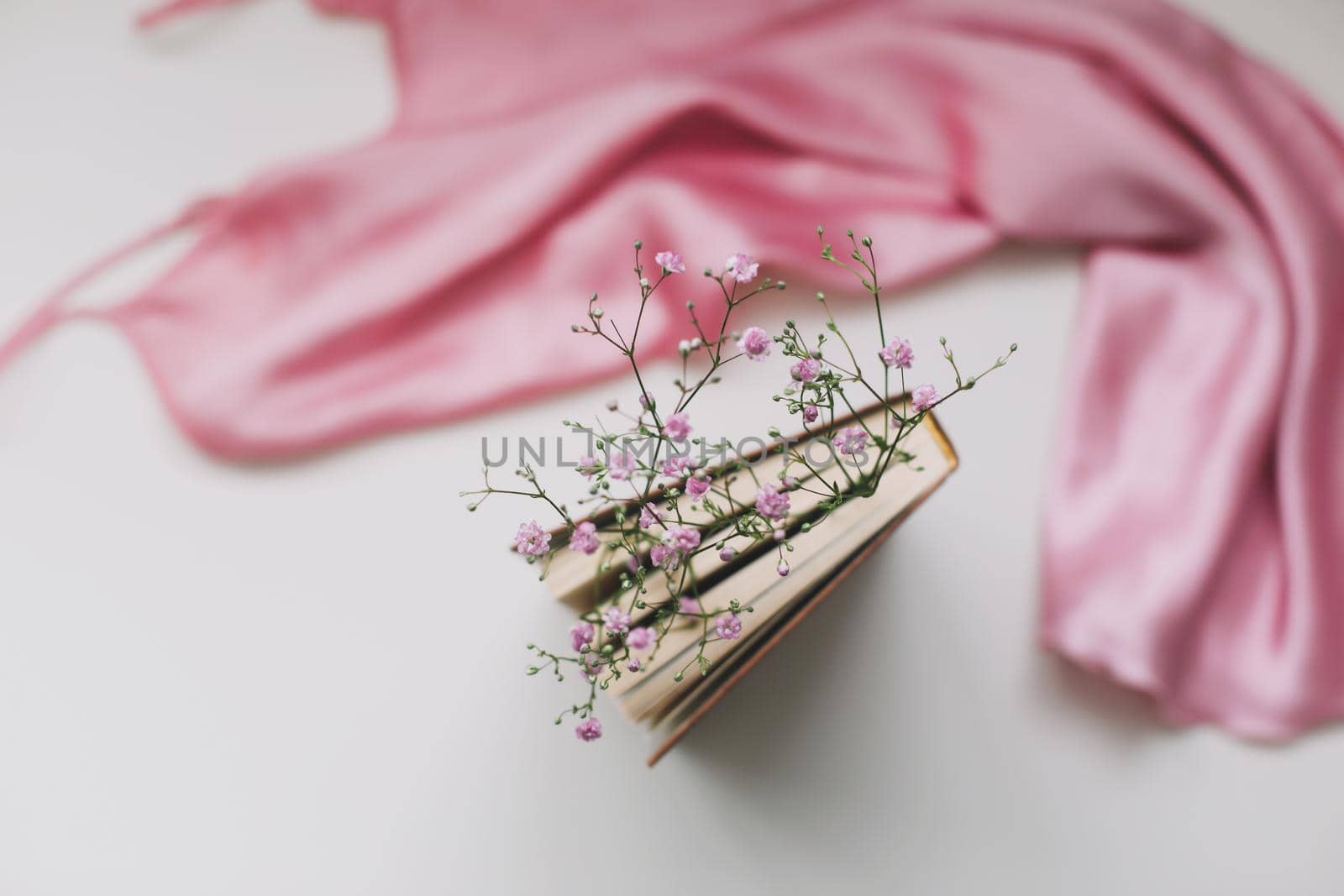 a book with flowers inside and pink silk fabric. Flat lay, top view, mock up