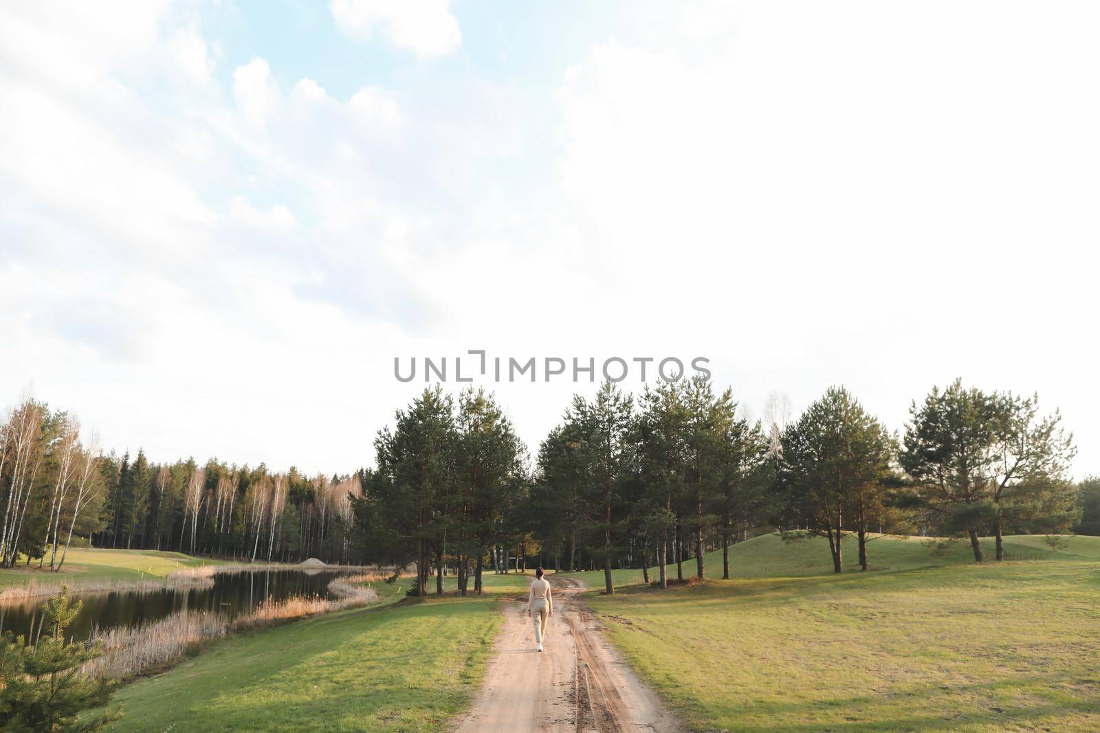 Beautiful colorful spring field and forest. silhouette of a woman walking on a path