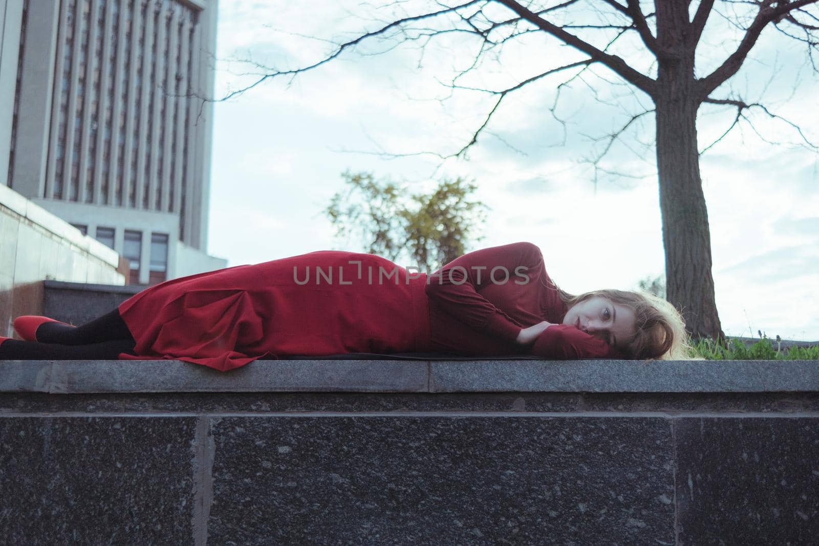 a blonde girl in red lies in the park by Symonenko