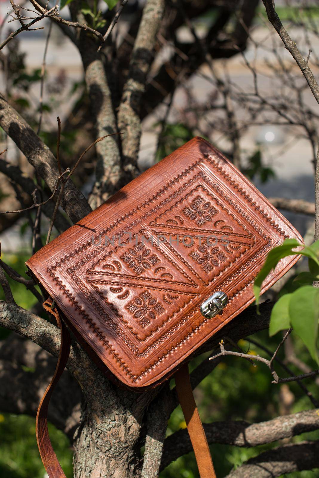 small orange women's leather bag with a carved pattern. street photo