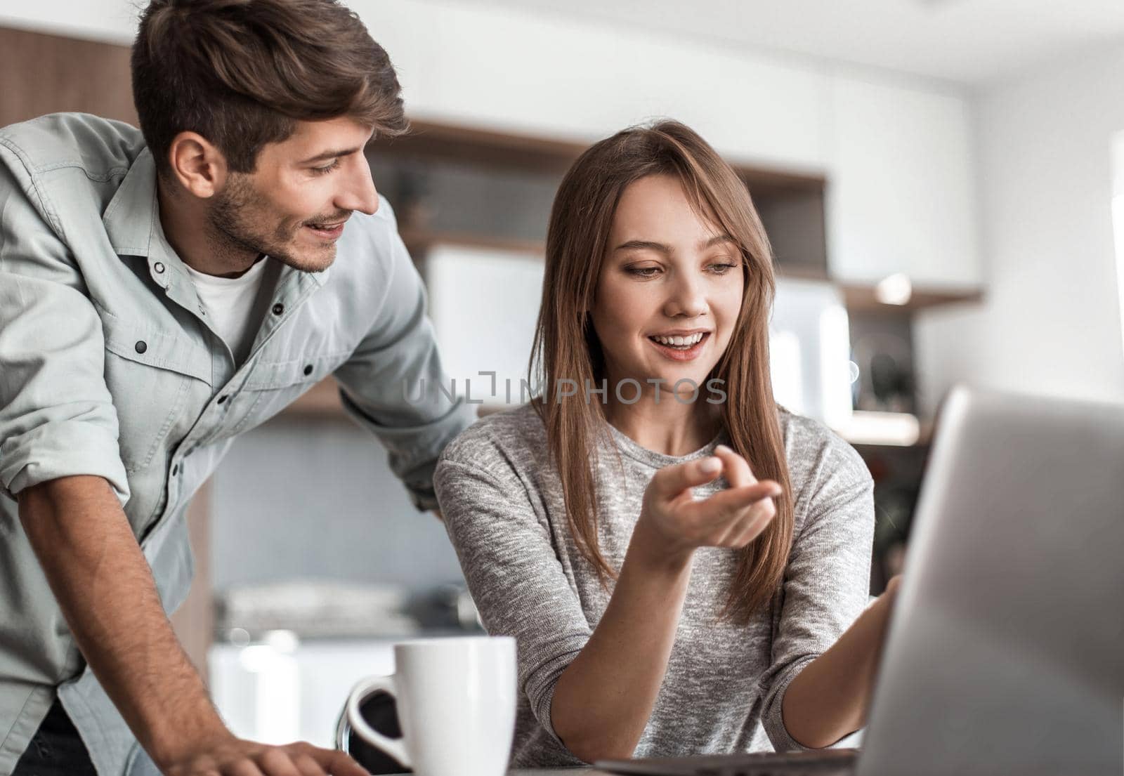 Cute couple using laptop together at home in the kitchen.people and technology