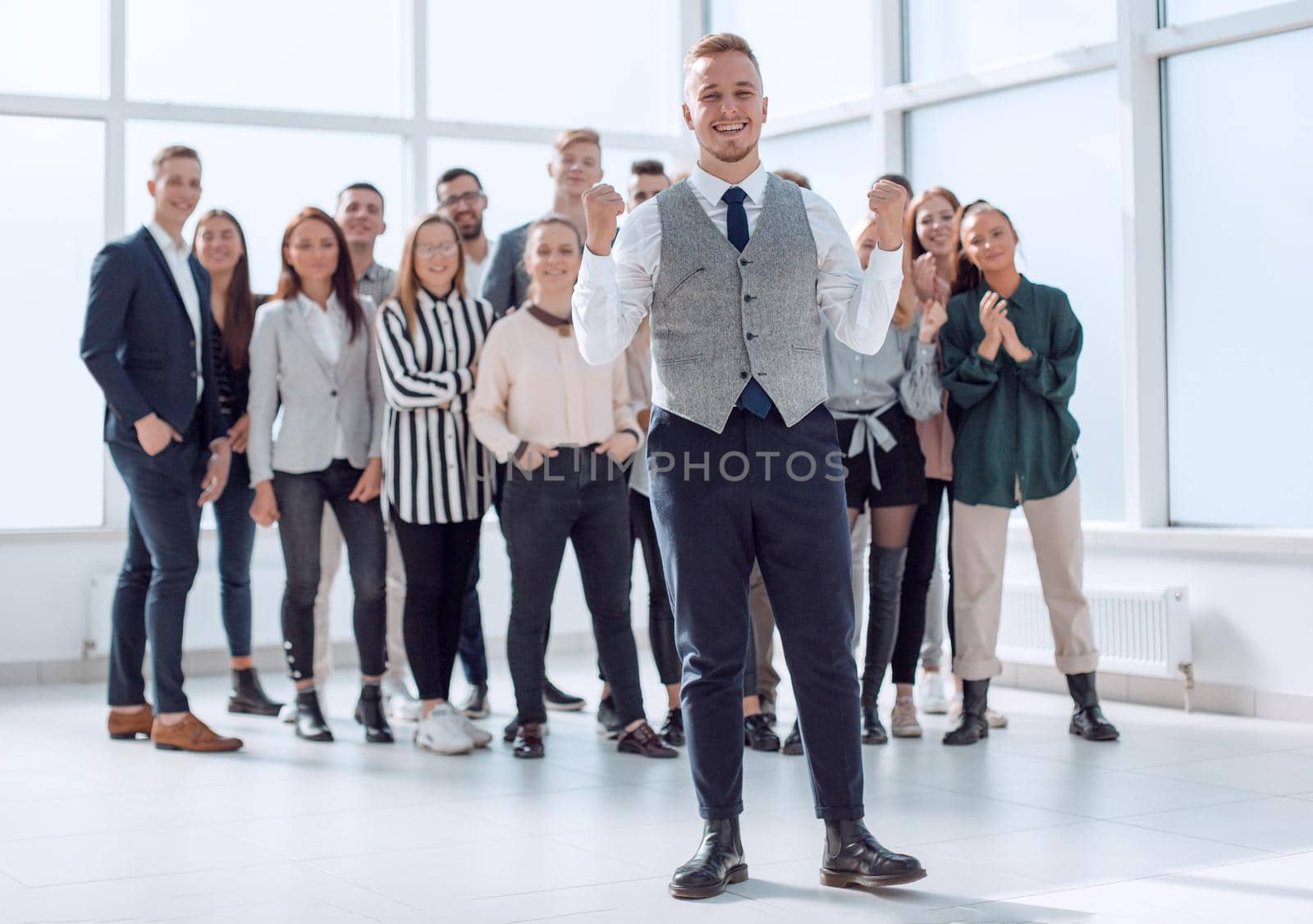 smiling young man standing in front of his colleagues by asdf