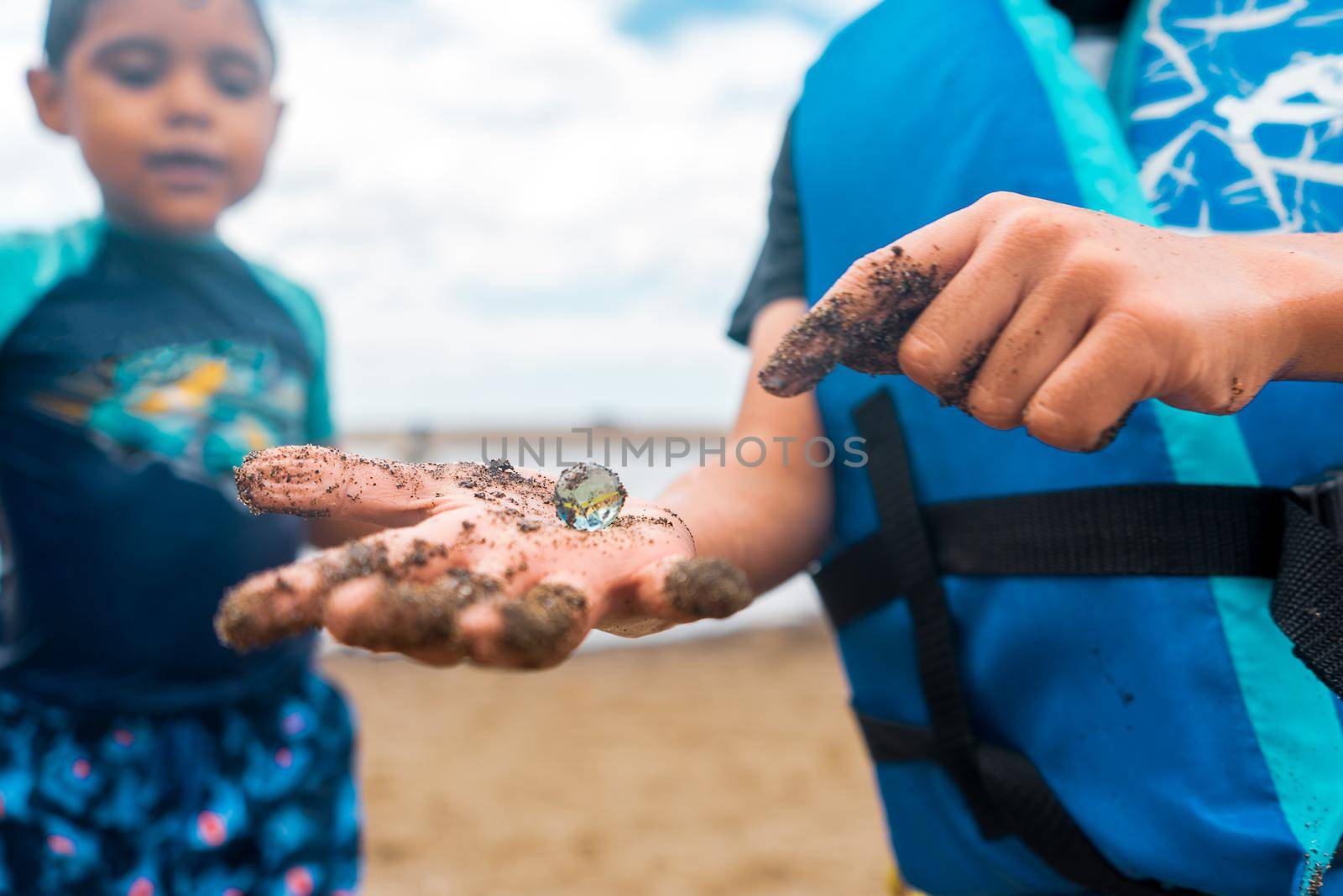Latin boy showing his brother a marble in his hand, a treasure he found digging on the beach during spring breake in Nicaragua.