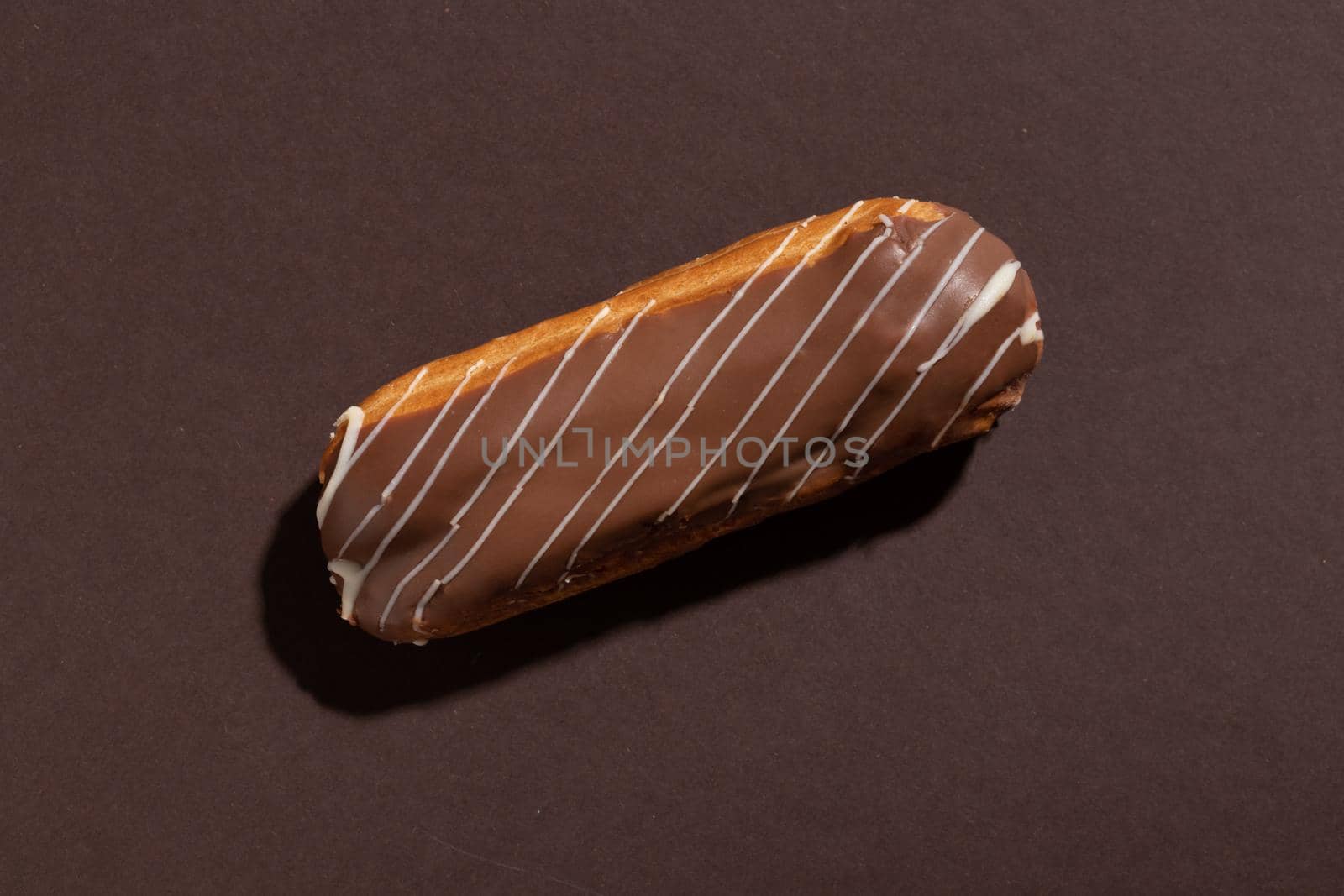 Chocolate eclair on a brown background top view