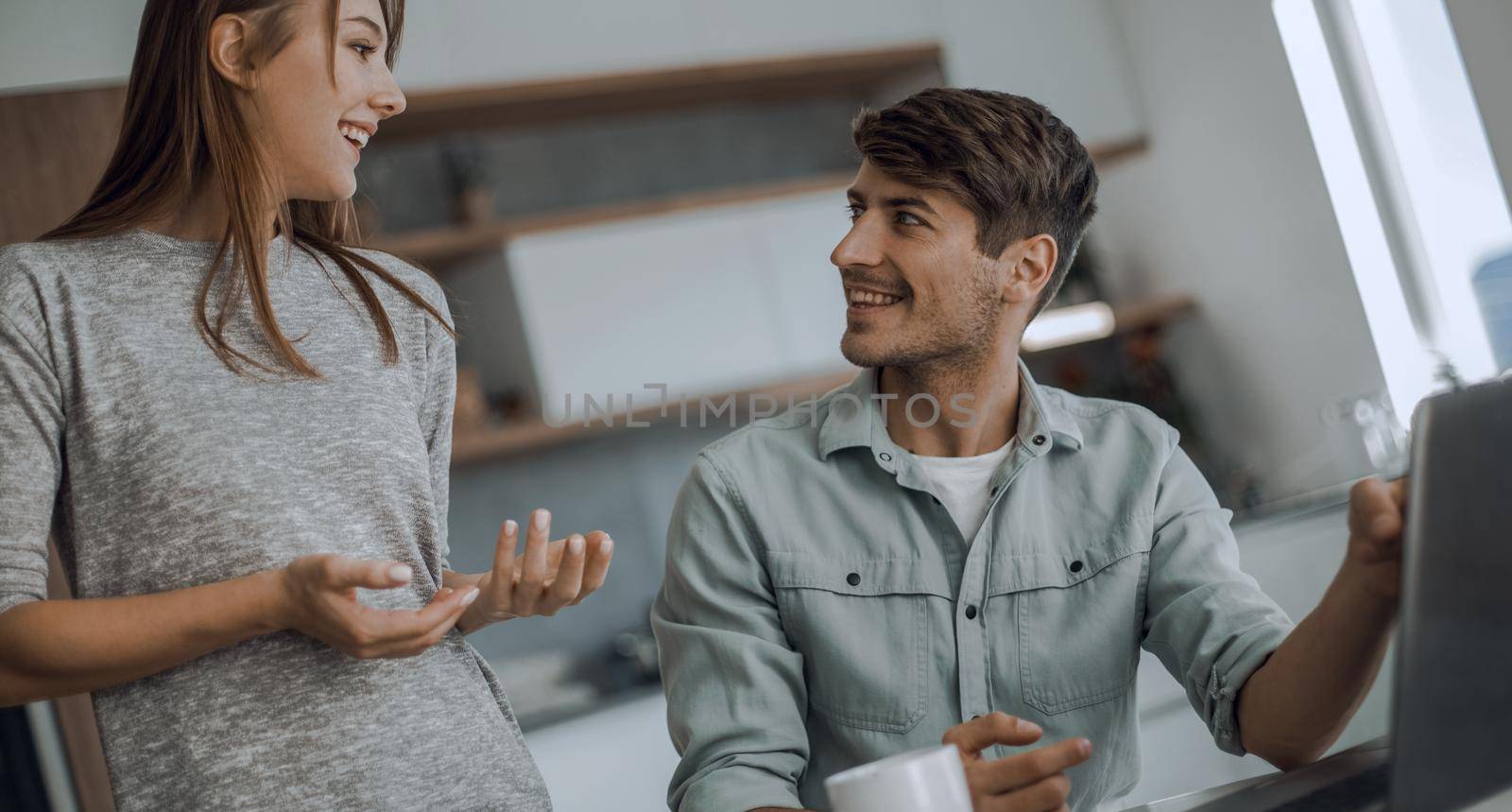 Young couple looking discussing online news in the kitchen. people and technology