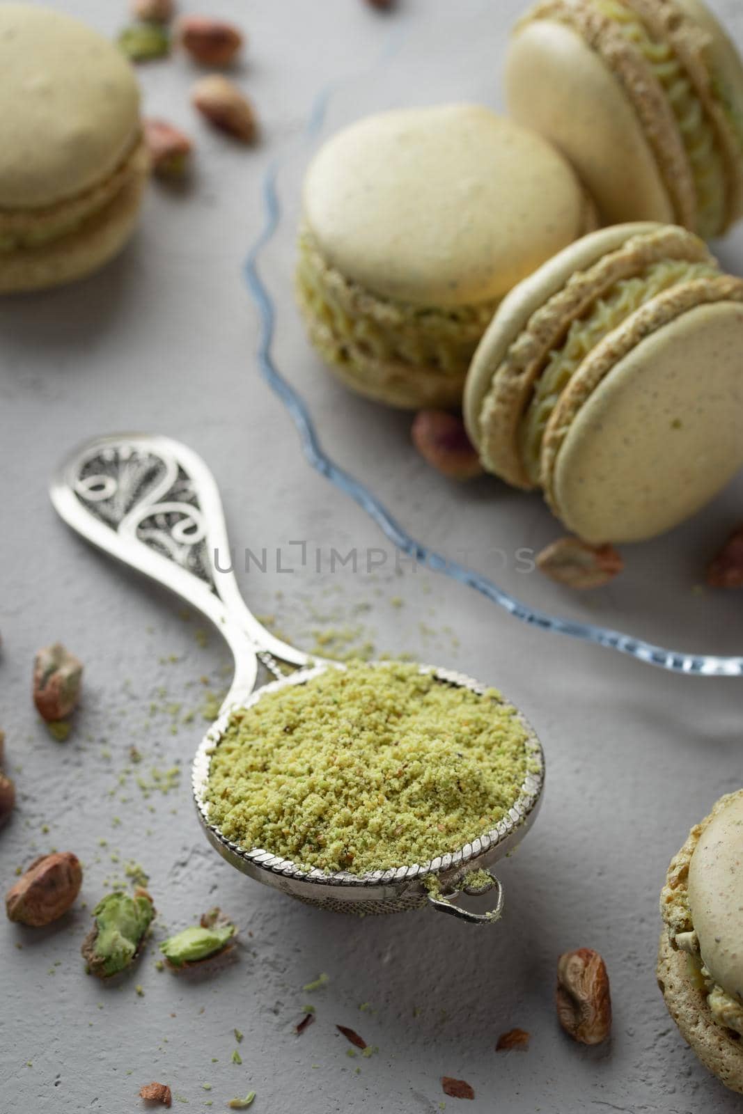 Pistachio flour and green macaroons on a gray background