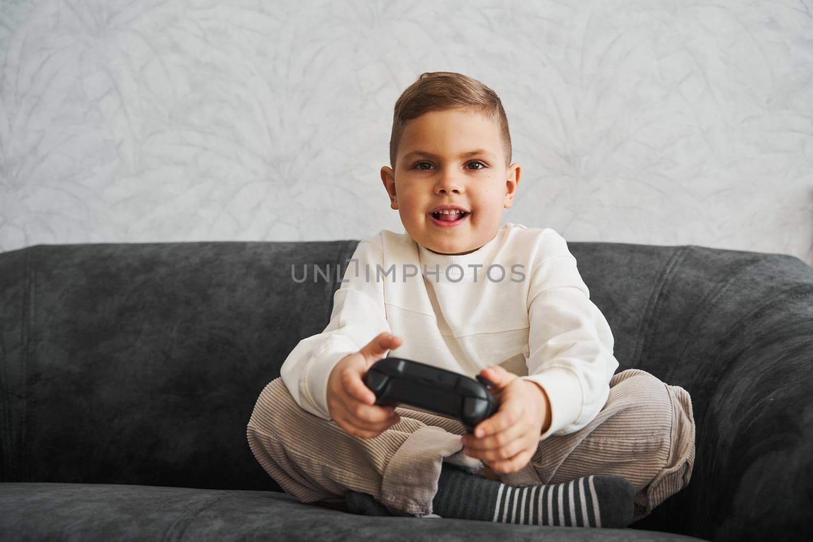 Happy child with gamepad at home. Boy is playing games. by Rabizo