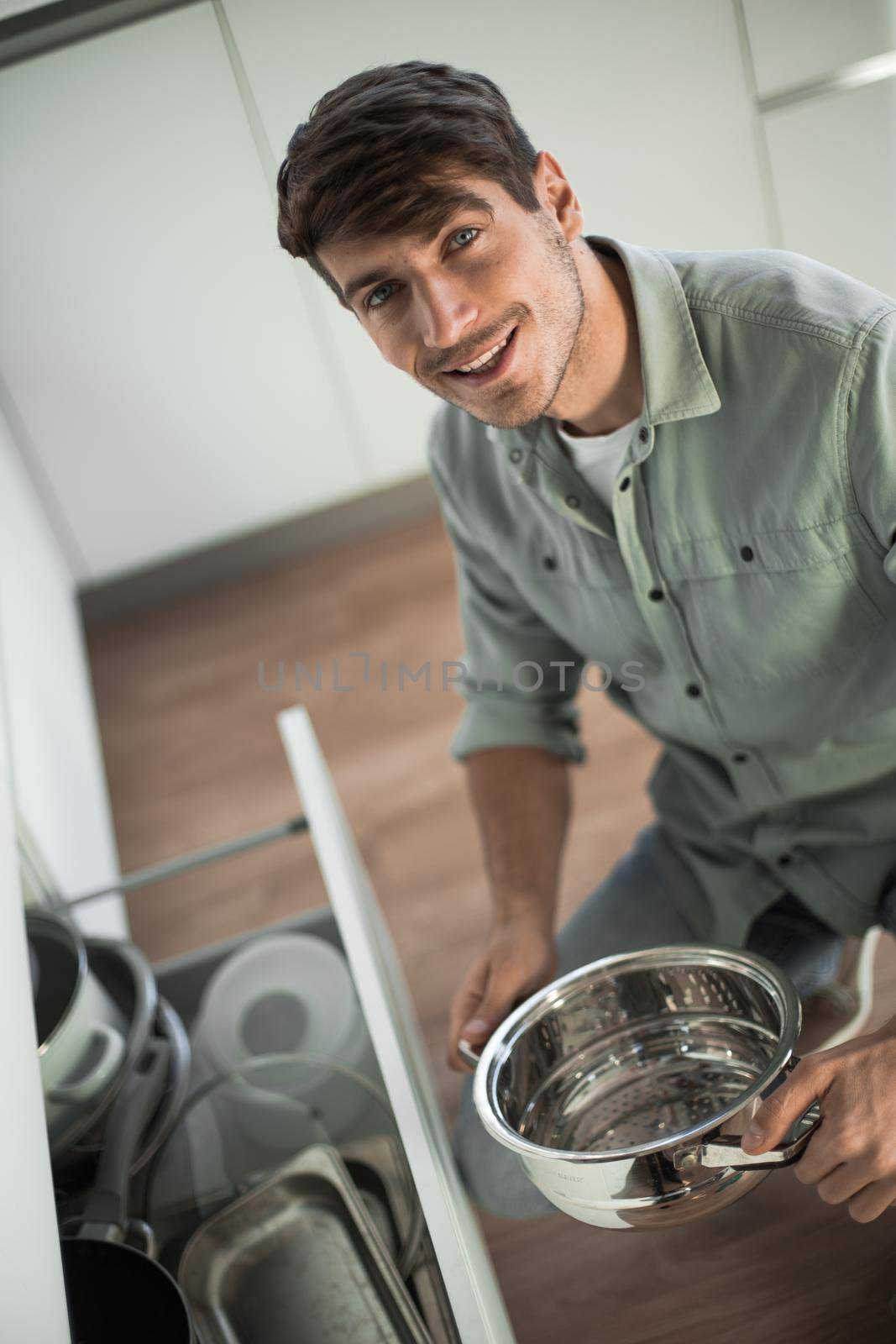 happy young man looking at clean dishes in dishwasher